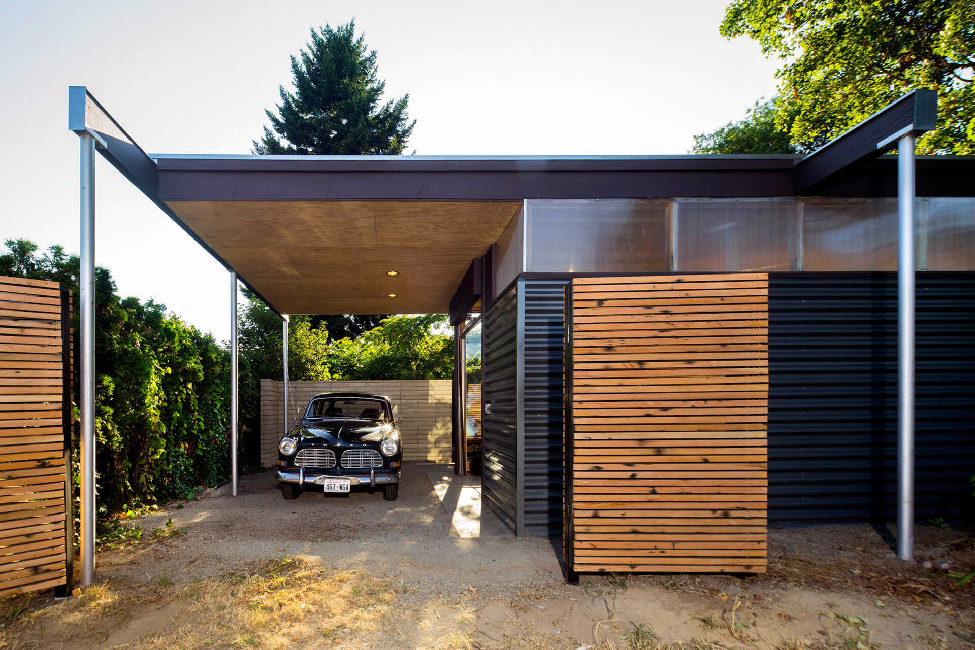 A pavilion roof extension creates a sheltered workspace and carport while keeping the footprint small.