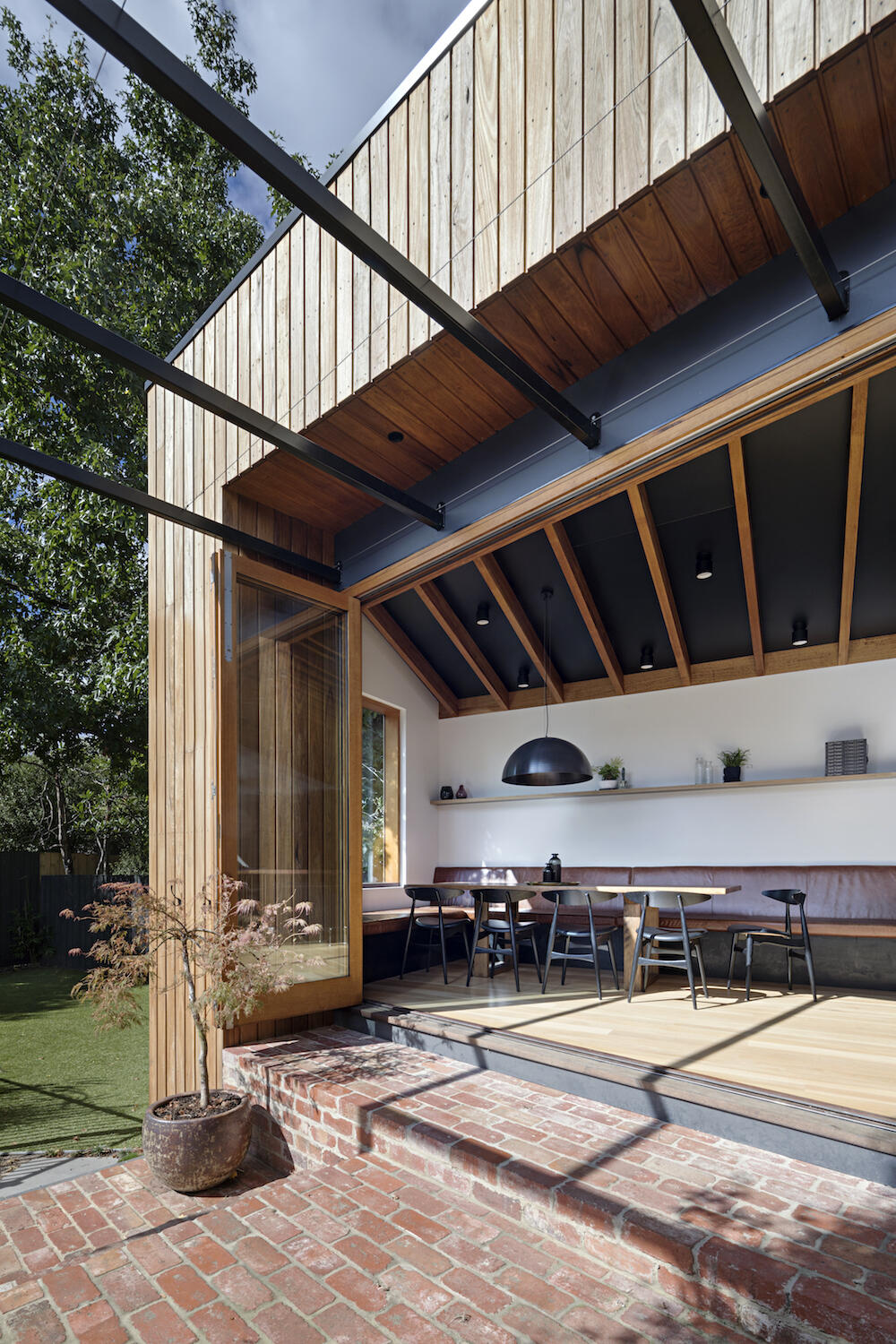 Wood framed glass doors open the dining area to the backyard and connect the interior to a brick patio, pool and yard.