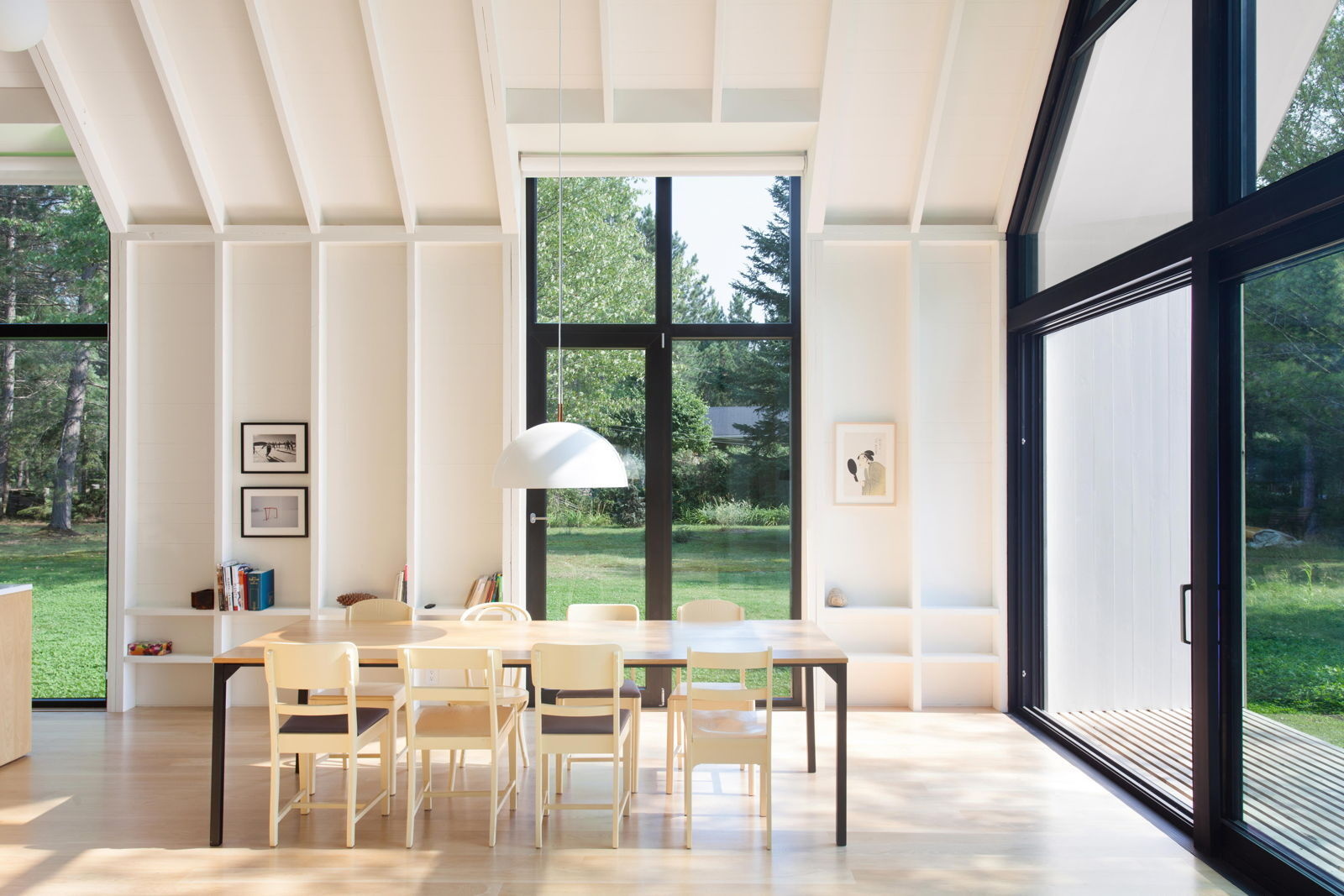 Los altos paneles de vidrio a cada lado desdibujan los límites entre la cabaña de cedro y el bosque exterior.