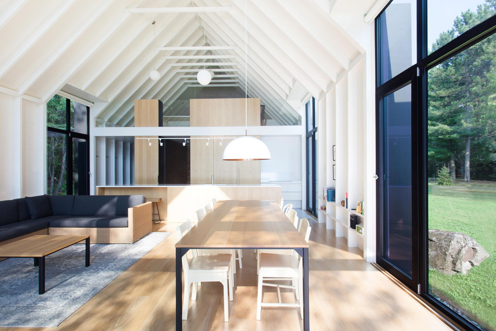 El espacio habitable de planta abierta cuenta con una pared totalmente acristalada que da al lago, lo que crea una pieza central tranquila y llena de luz para esta cabaña familiar.