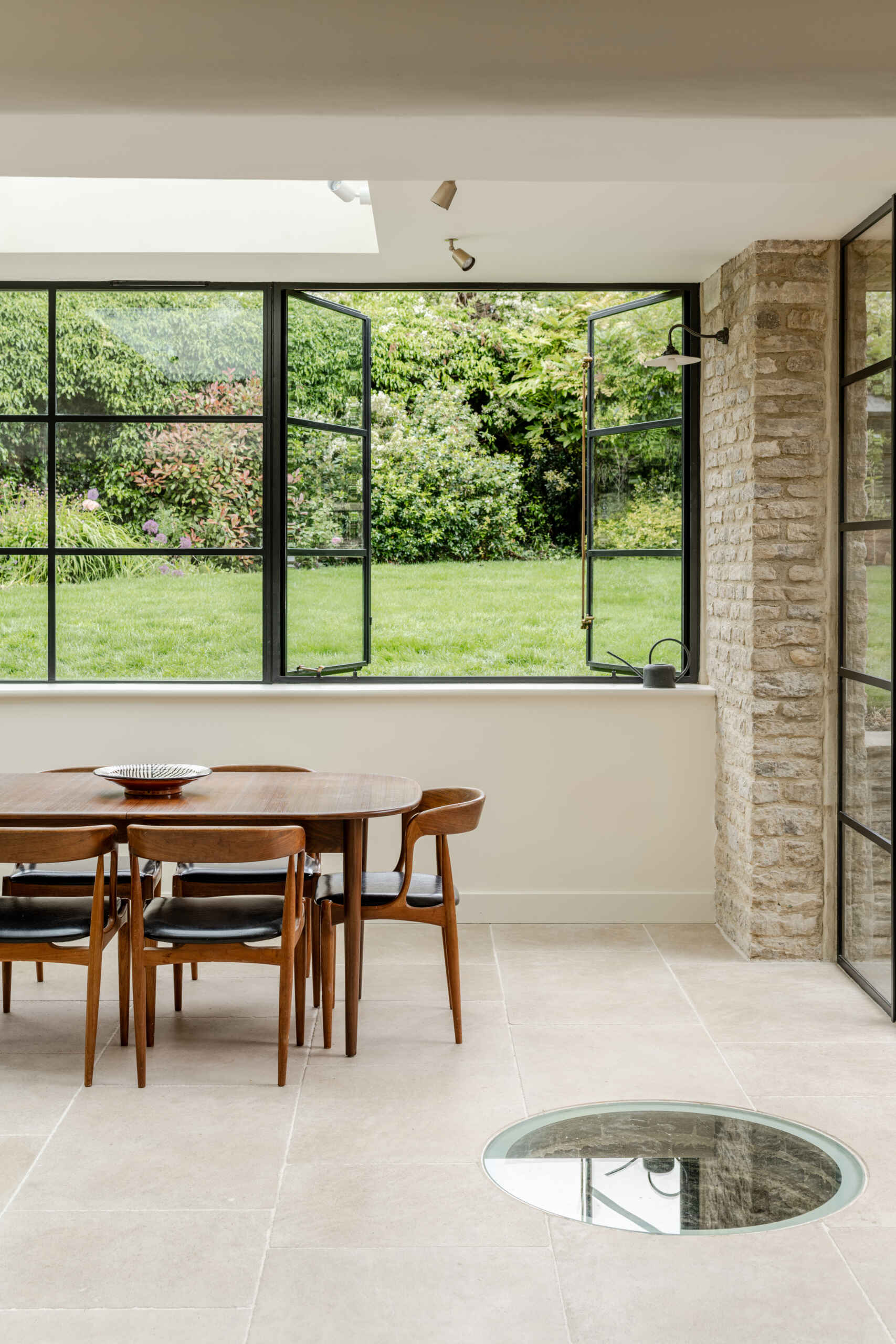 This new dining area gains natural light that moves across the space throughout the day. A historic well was uncovered during excavation. Instead of removing it, the team preserved it beneath a glass floor panel with subtle lighting. It now acts as a quiet focal point and a reminder of the site’s layered past.