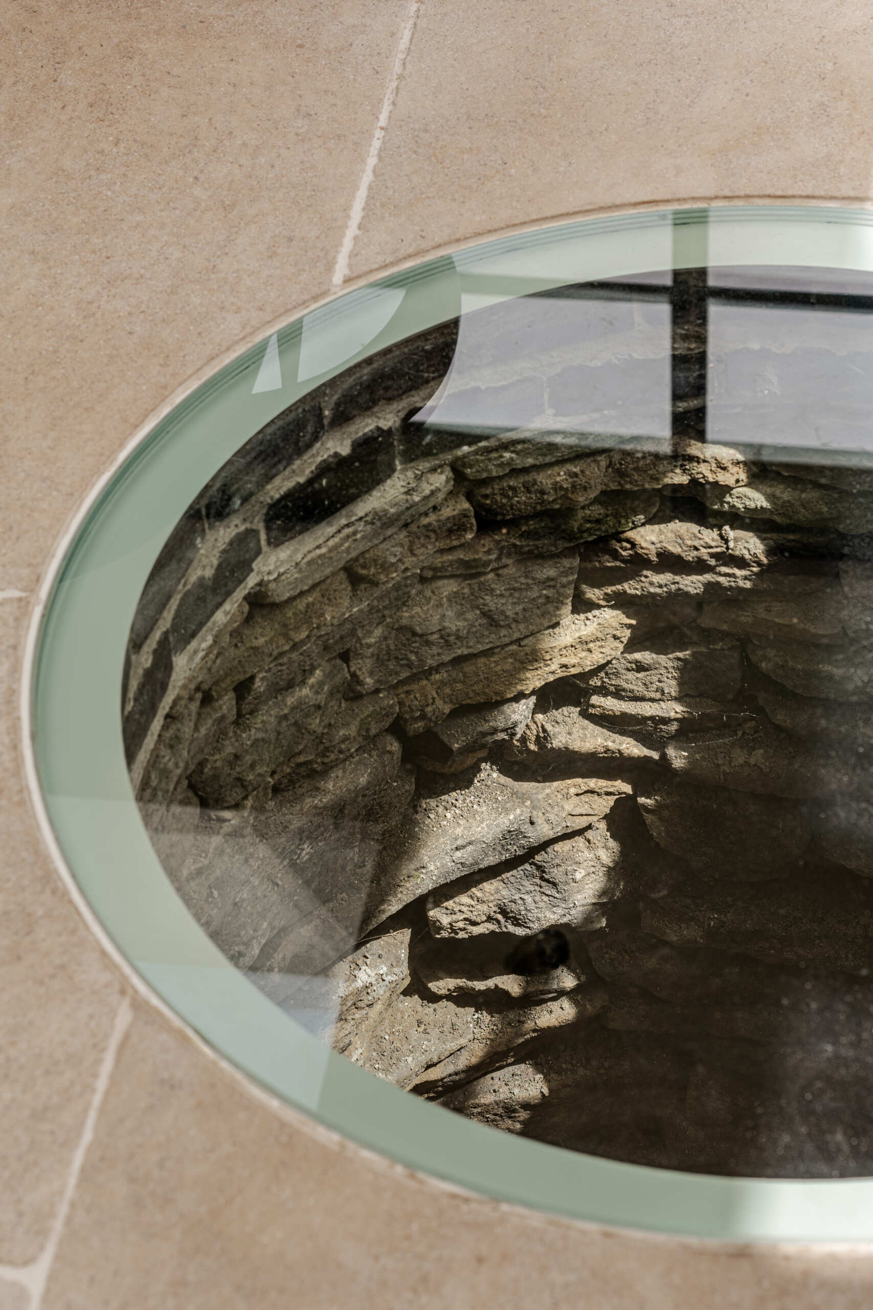 This new dining area gains natural light that moves across the space throughout the day. A historic well was uncovered during excavation. Instead of removing it, the team preserved it beneath a glass floor panel with subtle lighting. It now acts as a quiet focal point and a reminder of the site’s layered past.