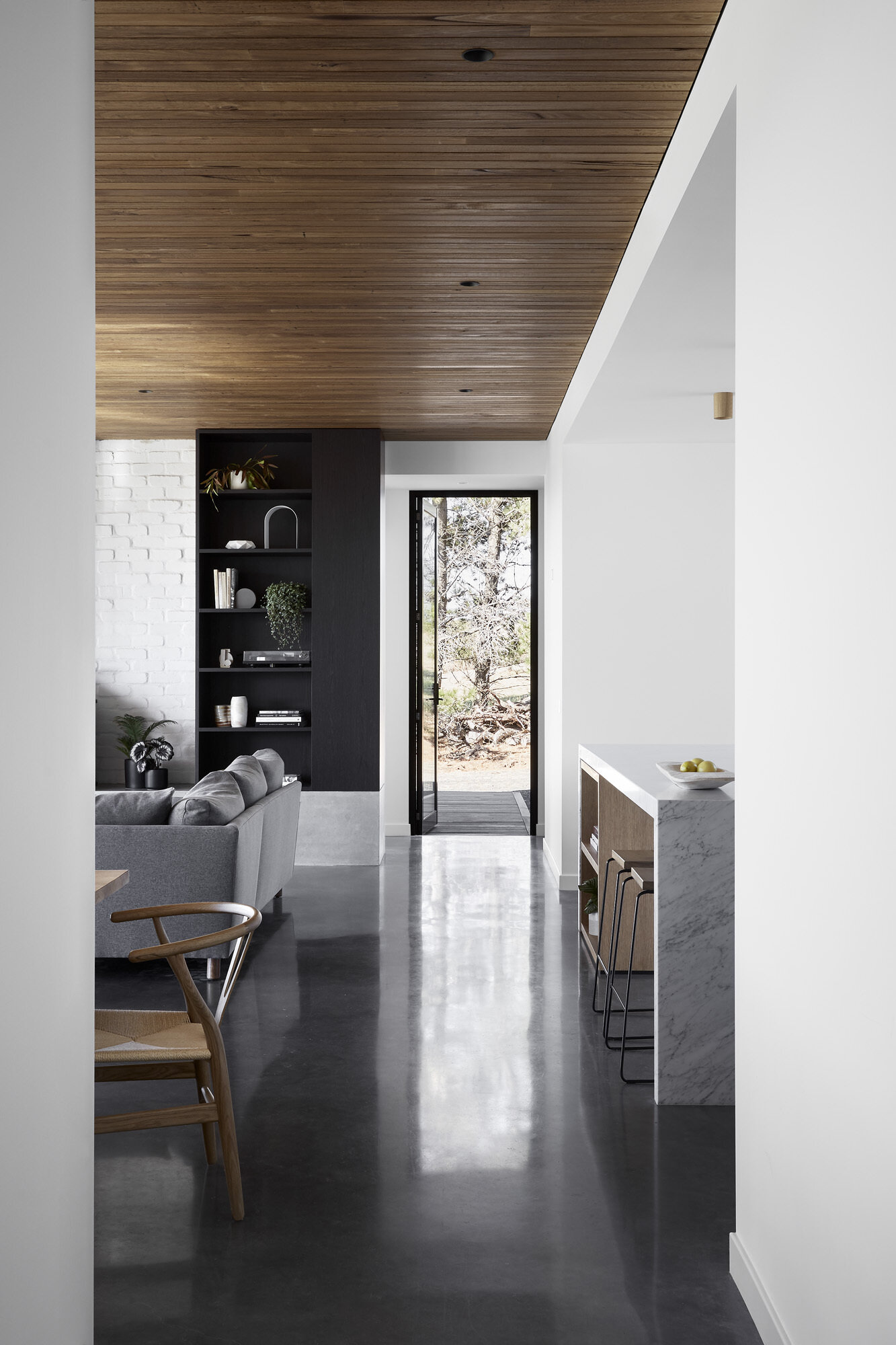 Timber ceilings and burnished concrete floors bring natural warmth and durability to the interior of this coastal home.