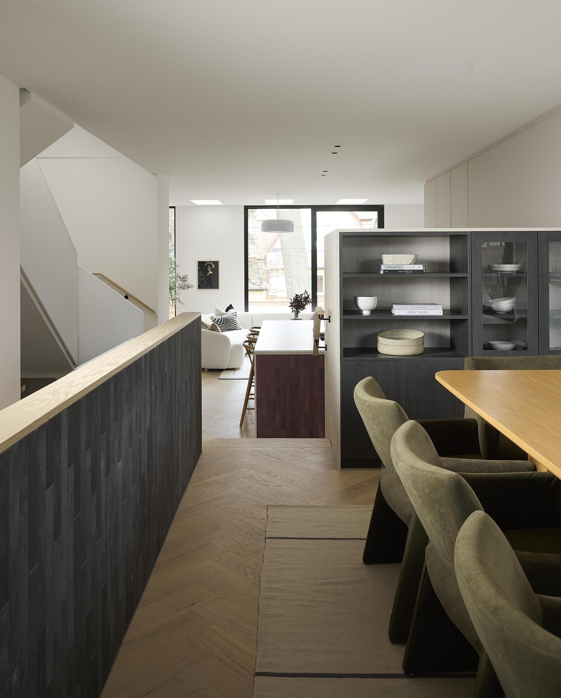 The dining area, accessed via a few steps, feels connected yet distinct, held by the warm tone of the oak cabinetry and the calm presence of the surrounding palette.