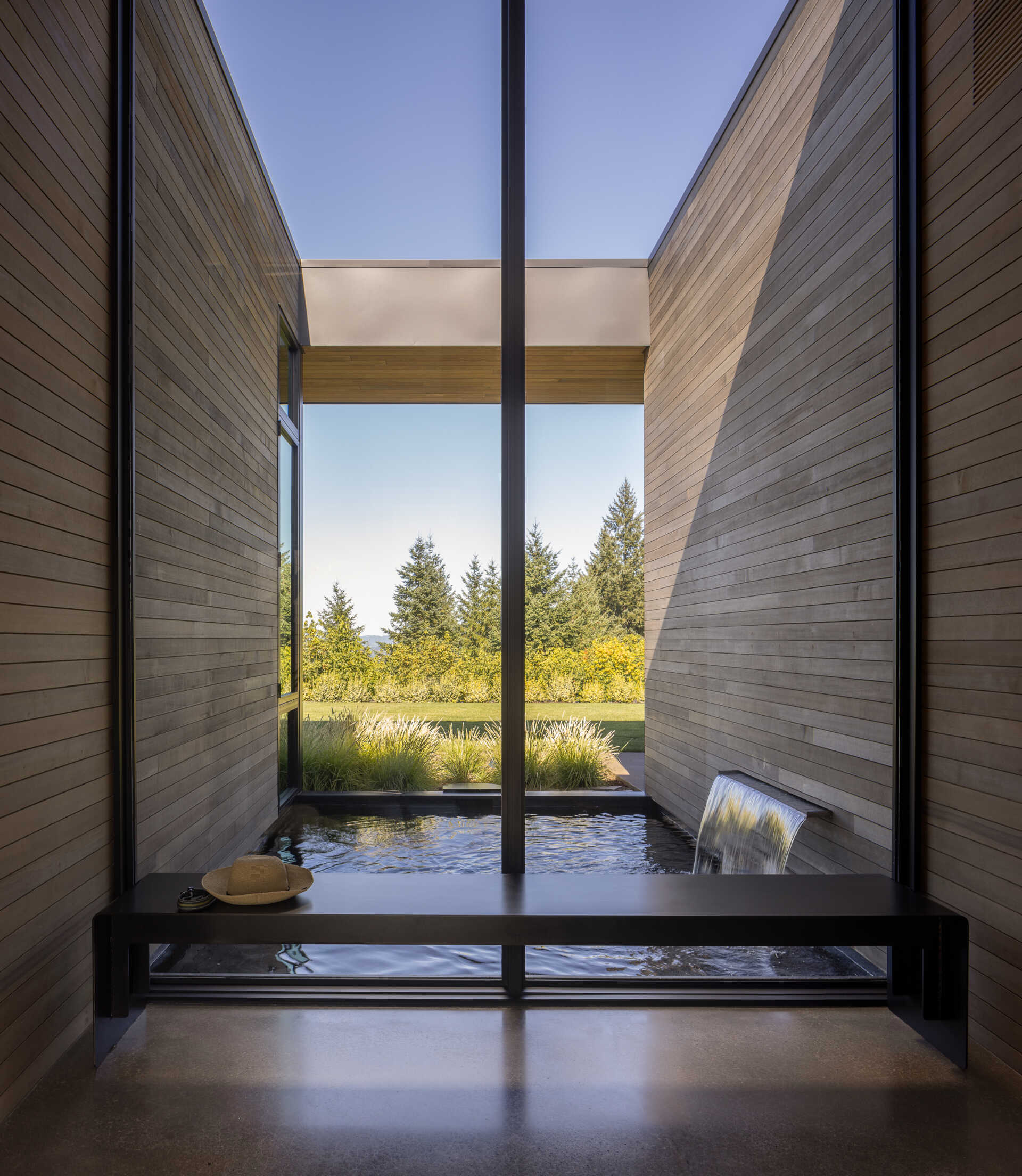 A custom bench sits beneath the glass, overlooking a recessed Koi pond that is protected on three sides of the home. 