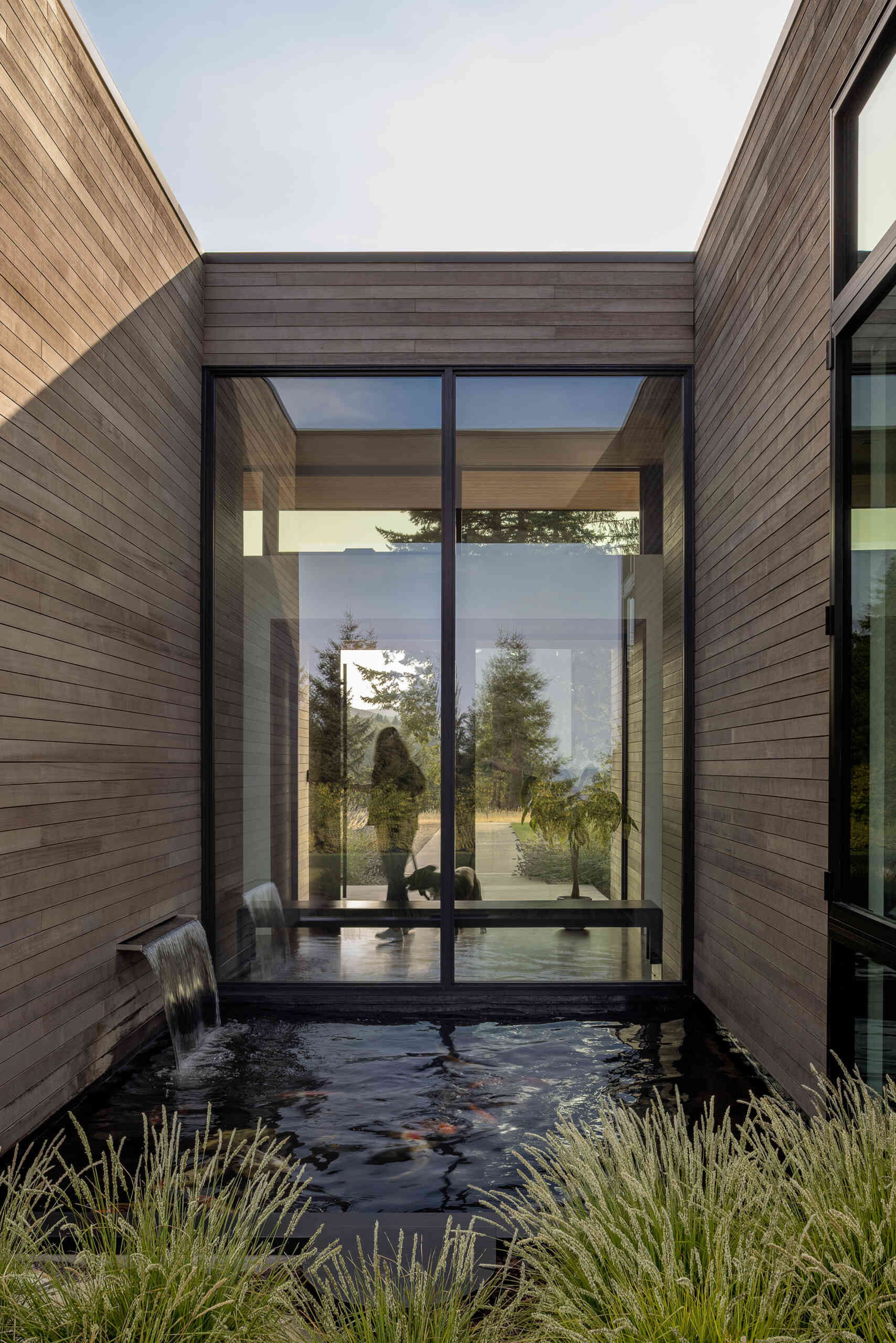 A custom bench sits beneath the glass, overlooking a recessed Koi pond that is protected on three sides of the home. 