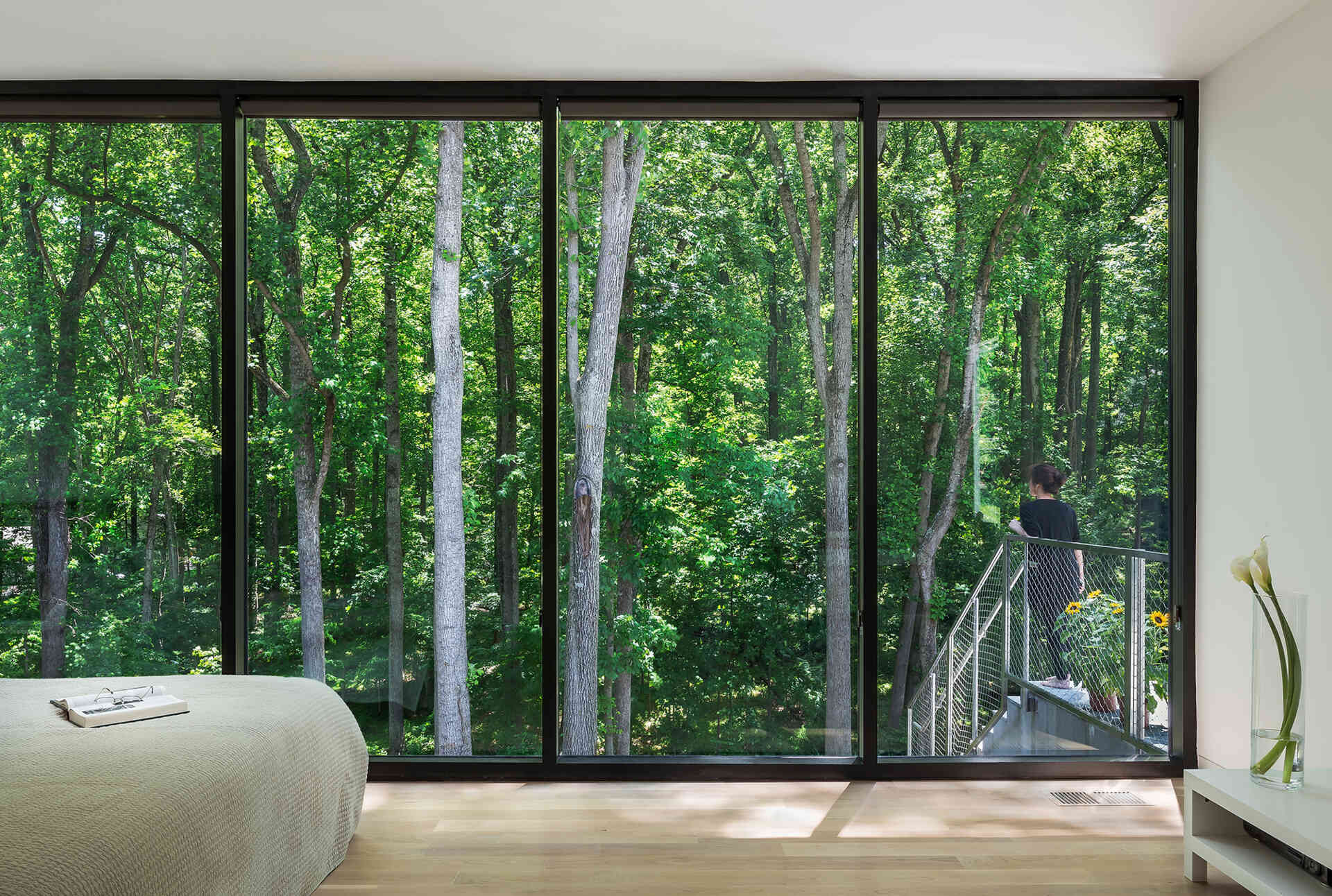 A modern bedroom where floor-to-ceiling windows turn the forest into part of the room.