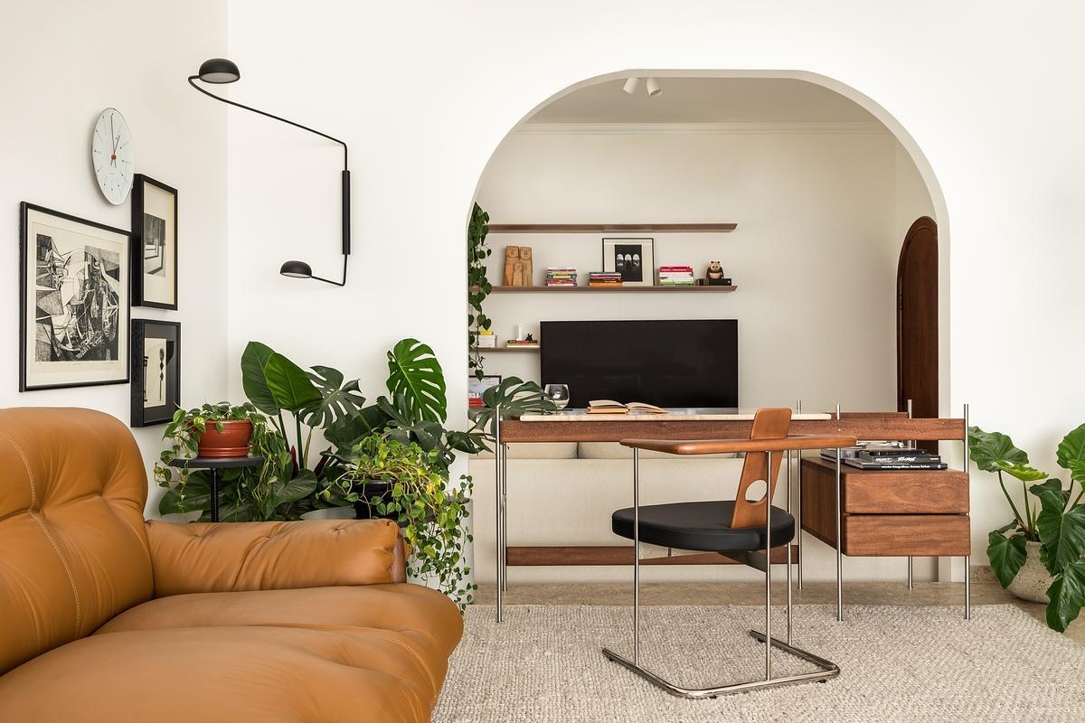 A secondary living area is organized around the Sofá Mole by Sérgio Rodrigues. The Mole Sofa sits beside the Estrado Desk by Gustavo Bittencourt, making this zone both comfortable and functional. An archway frames views through to the TV room, creating layered perspectives that link relaxation and work. Art and a 1978 woodcut by Burle Marx sit nearby, anchoring the space in Brazilian modernist tradition without overwhelming daily life.