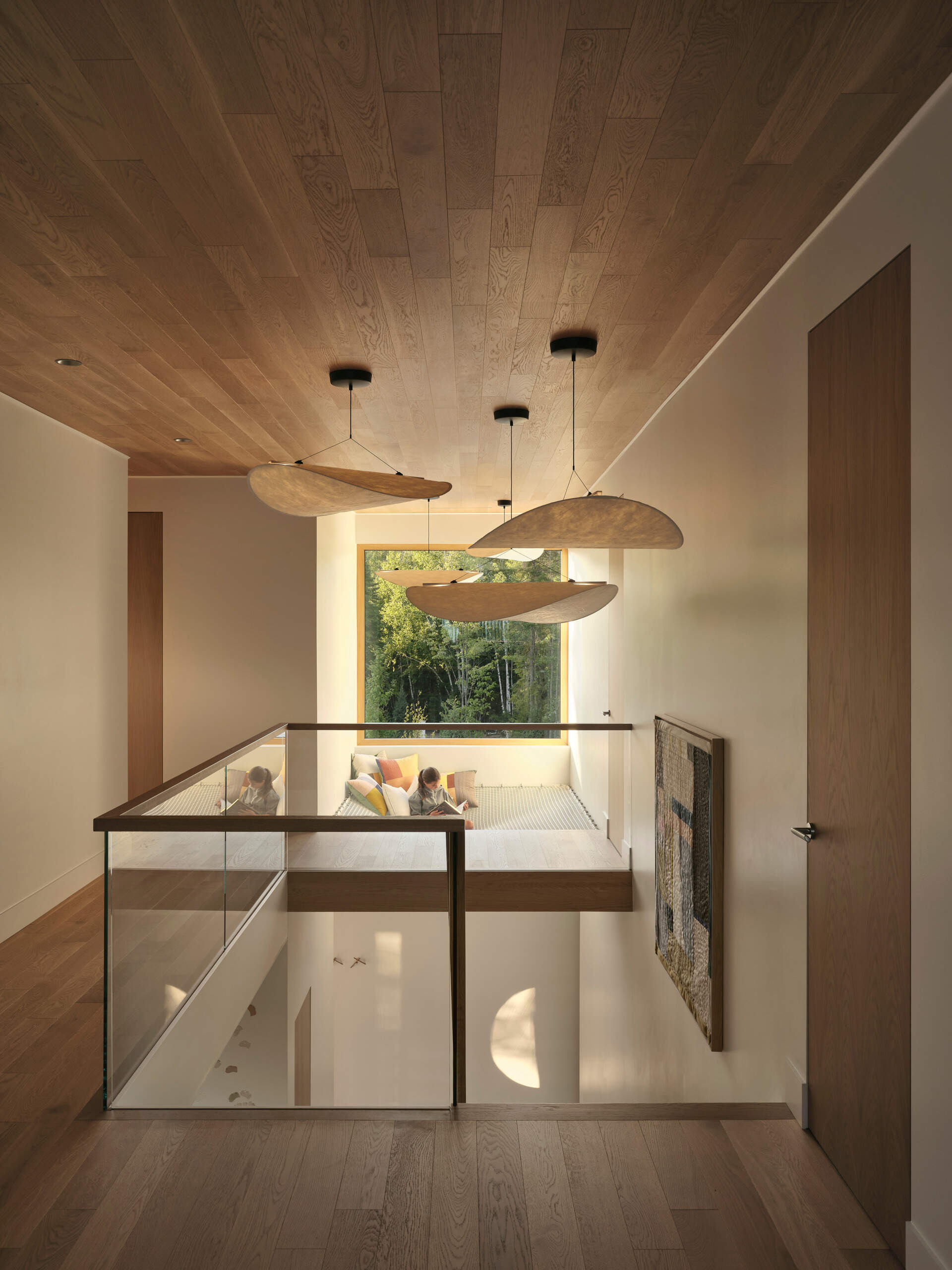 A light-filled staircase connects the different levels, with pale wood steps echoing the natural palette used throughout the home. Above, a suspended net loft creates a cozy nook for reading or daydreaming.