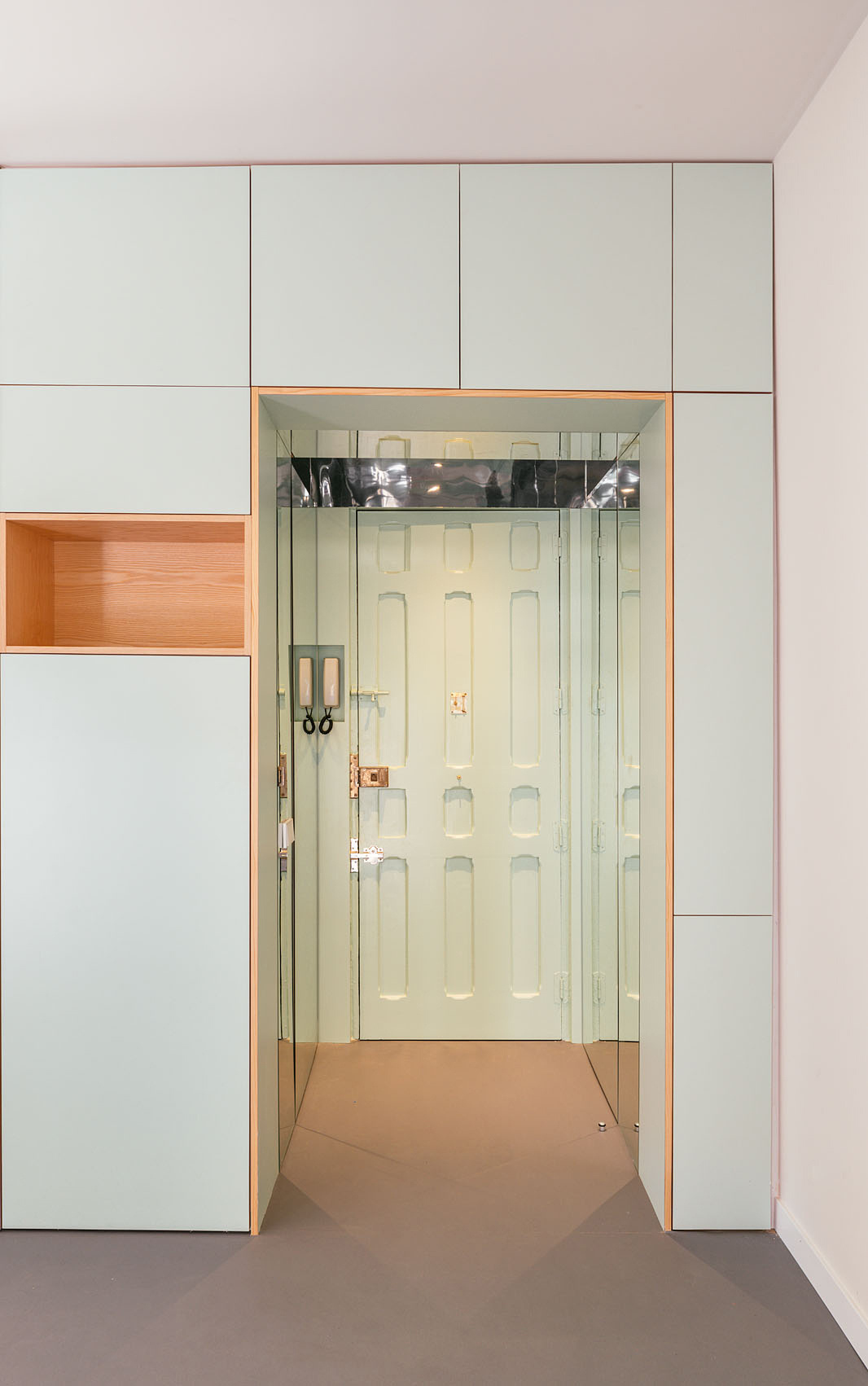 A mirrored entryway expands the feel of this compact Madrid apartment with reflections that draw daylight through the entire space.