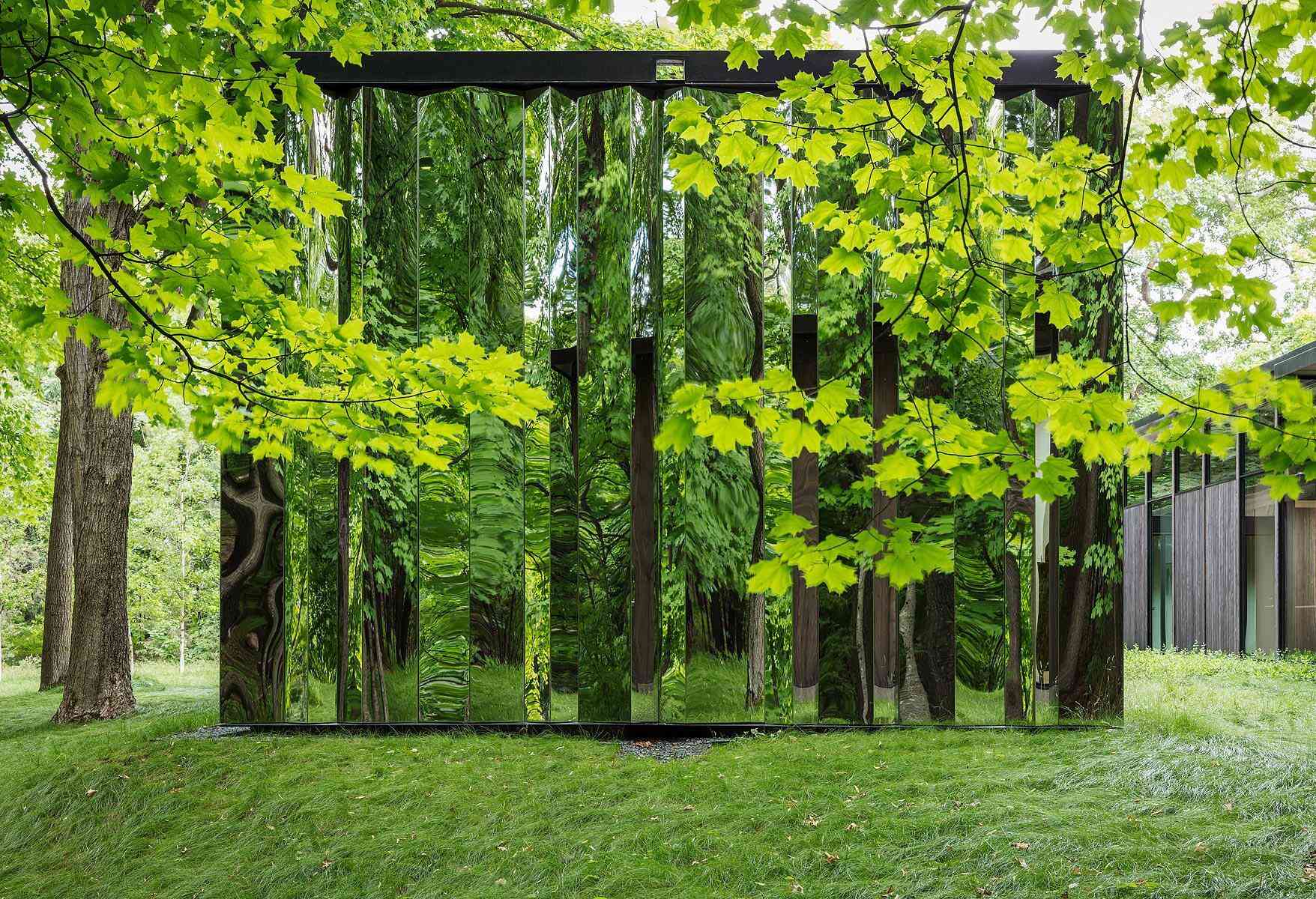 A reflective storage shed that melts into the woods with mirrored surfaces.