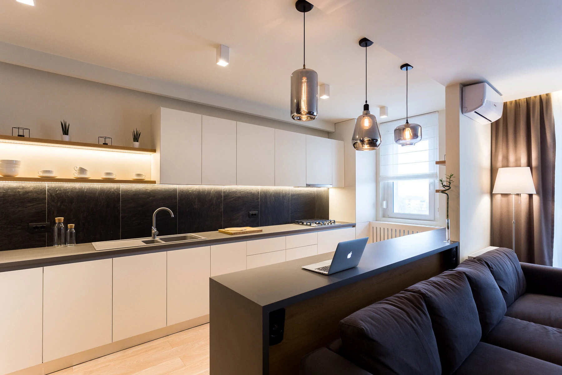 La cocina abierta cuenta con iluminación empotrada, elegantes accesorios negros y una barra versátil que fluye perfectamente hacia la sala de estar.