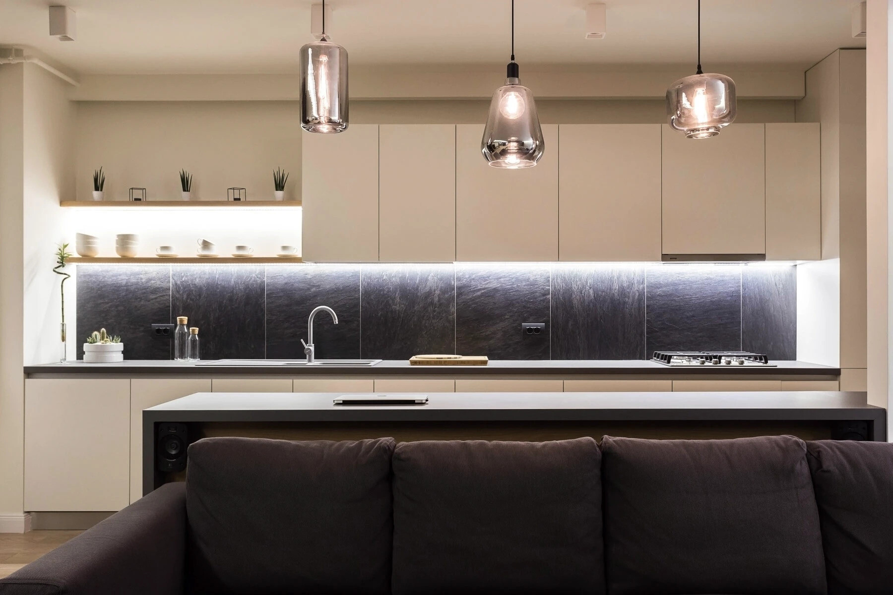 La cocina abierta cuenta con iluminación empotrada, elegantes accesorios negros y una barra versátil que fluye perfectamente hacia la sala de estar.