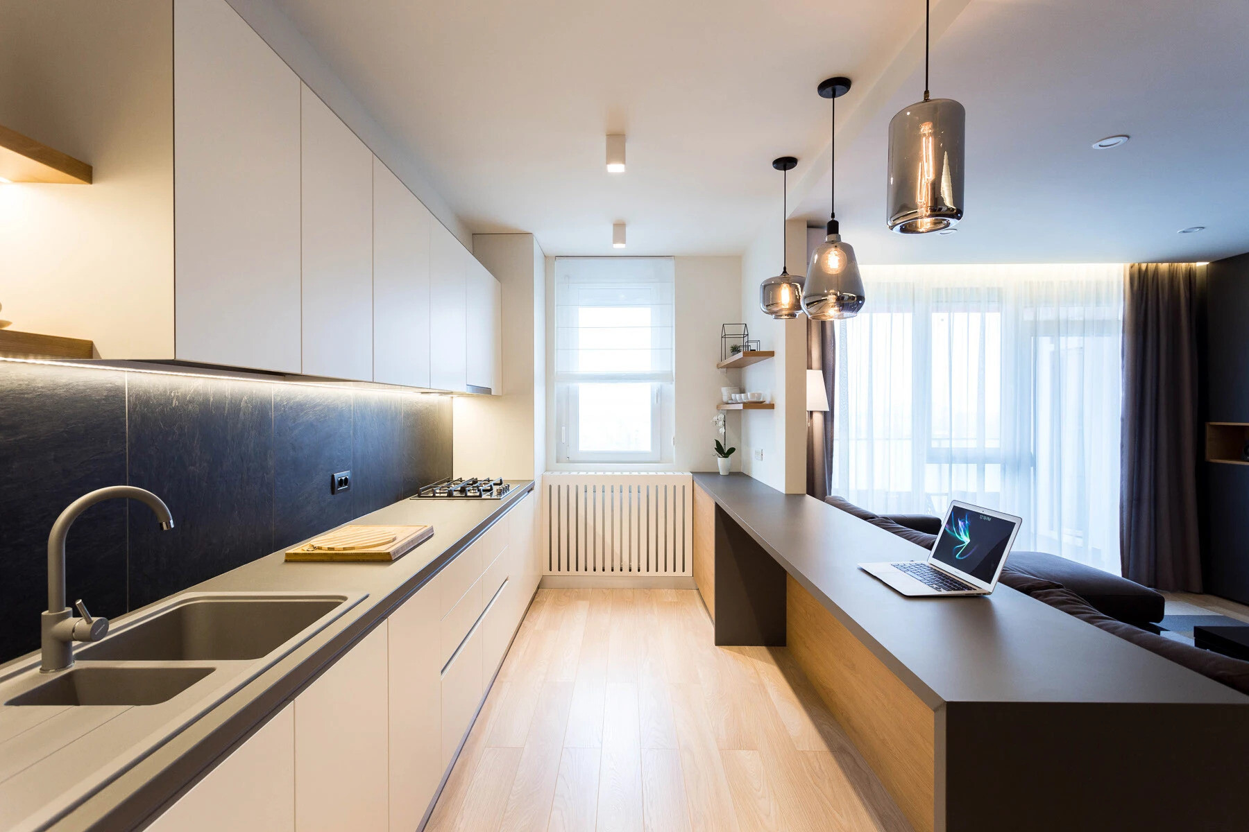 La cocina abierta cuenta con iluminación empotrada, elegantes accesorios negros y una barra versátil que fluye perfectamente hacia la sala de estar.