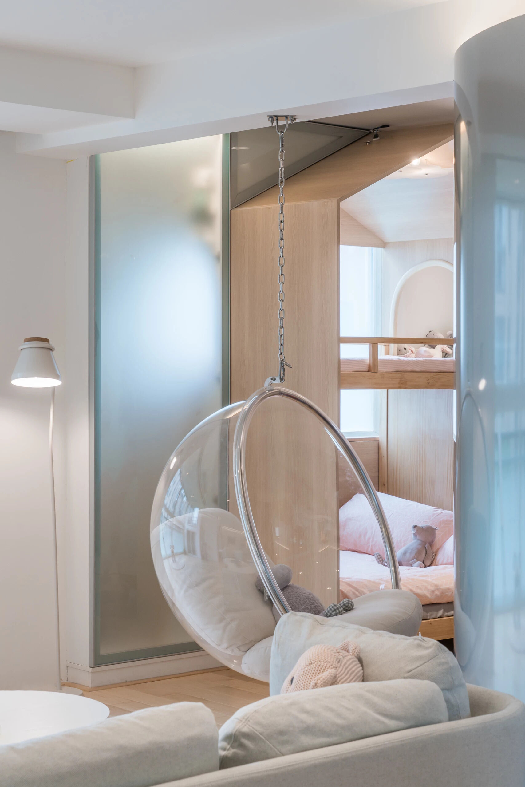 A bright living room filled with plants, light, and a clear hanging chair that bridges family spaces.