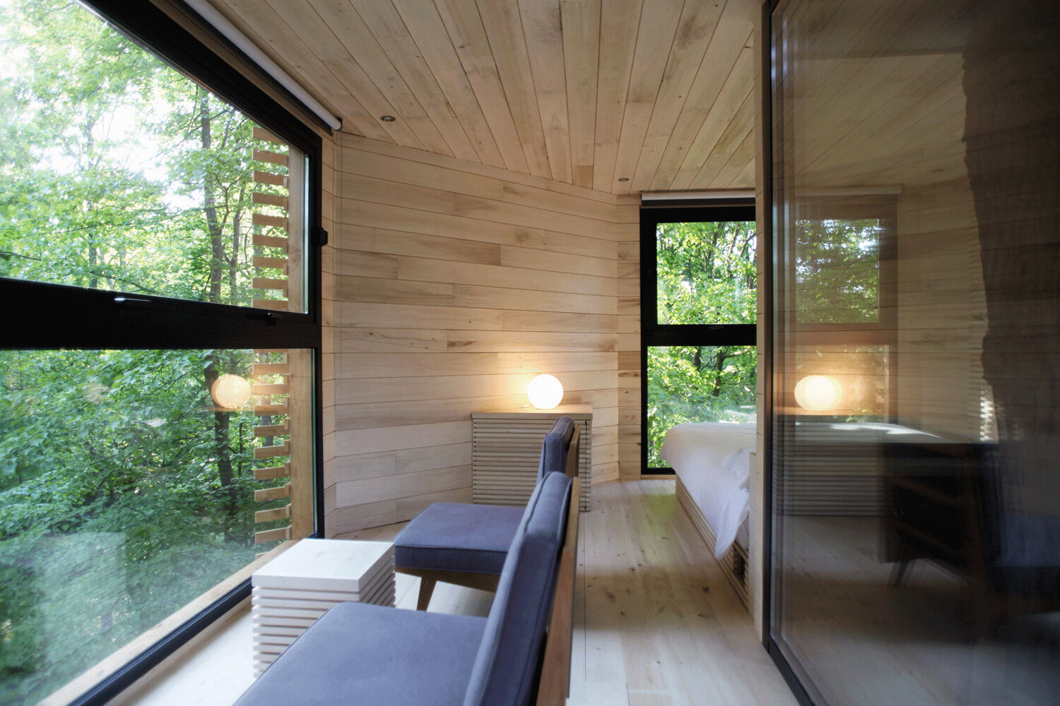 Inside the ORIGIN Treehouse, light poplar wood and panoramic windows create a warm, minimalist retreat suspended among ancient oaks.