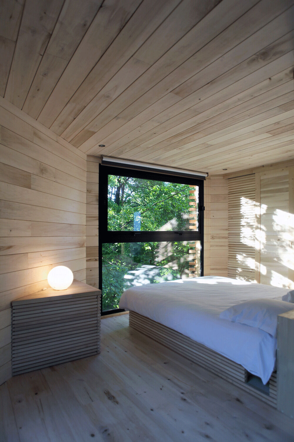 Inside the ORIGIN Treehouse, light poplar wood and panoramic windows create a warm, minimalist retreat suspended among ancient oaks.