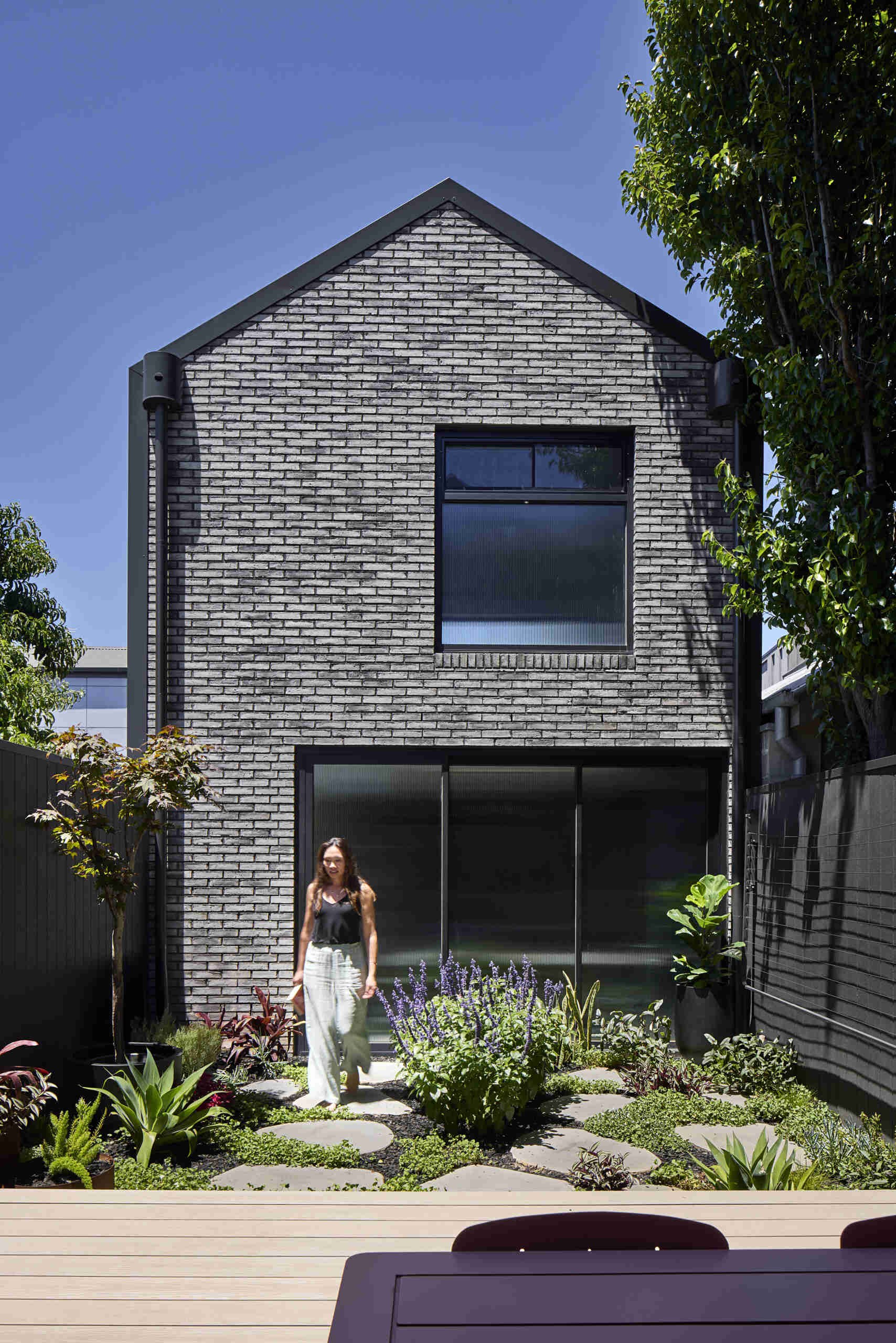 Fluted glass sliding doors on the garage bring daylight into a space that is usually dark. These doors slide into a single stack, allowing the garage to operate as a flexible secondary living zone.