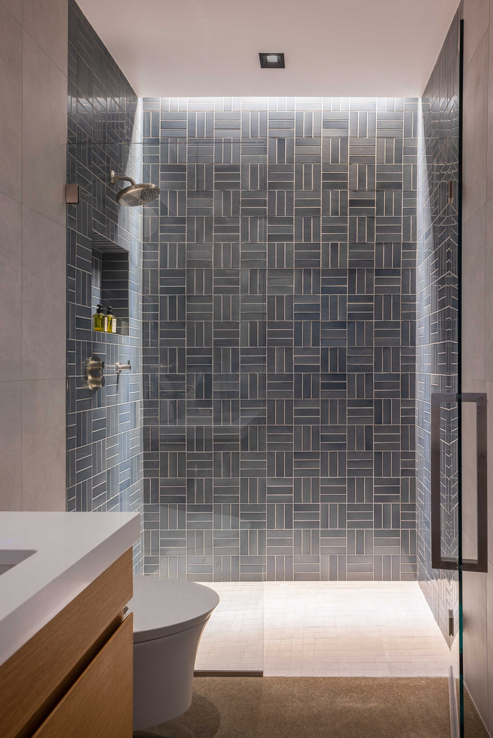 This modern bathroom maintains the same restrained palette and warm minimalism, echoing the home’s architectural language. Light, clean lines, and practical comfort shape a space intended for guests while still keeping the material continuity of the rest of the home.