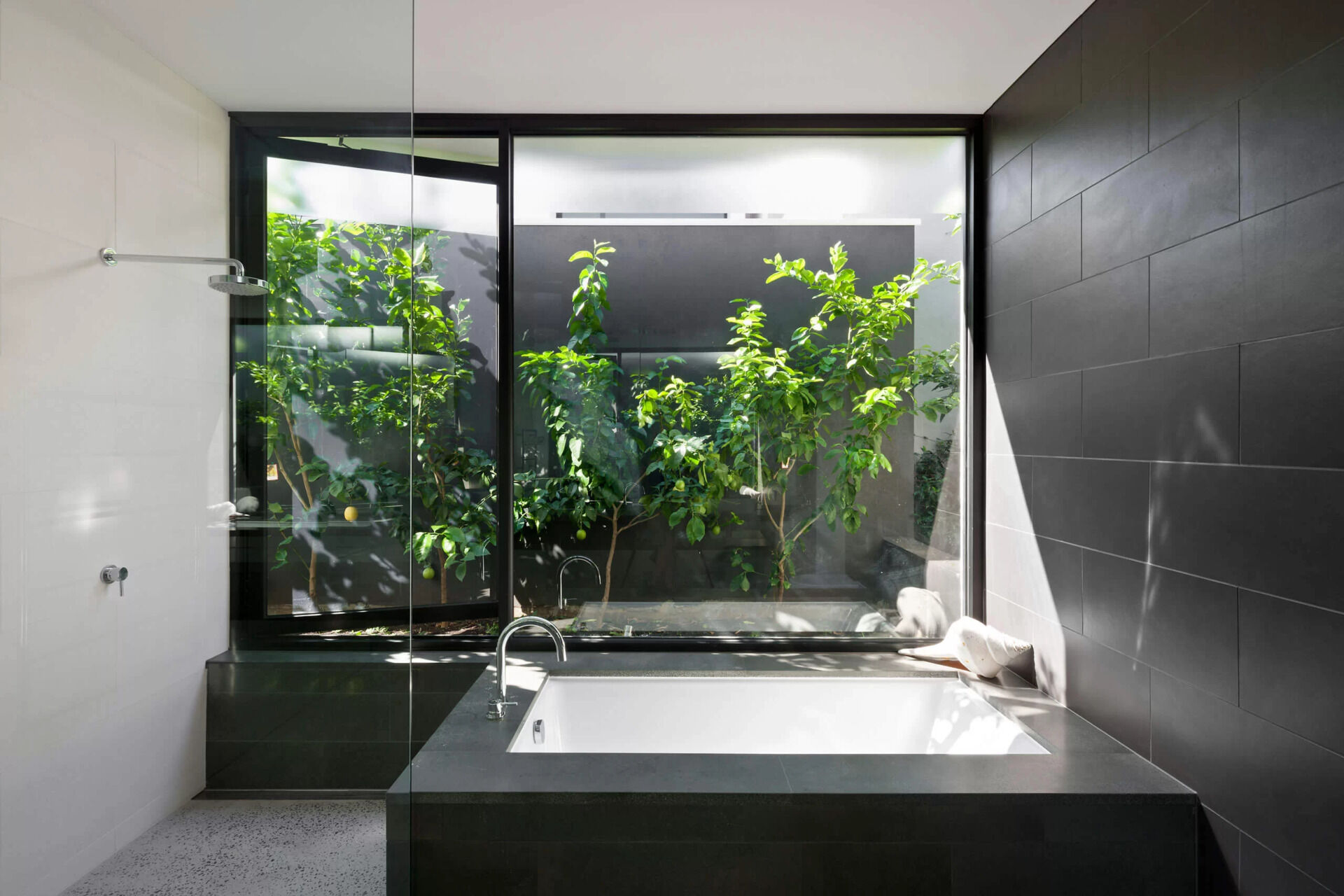 A bathroom with a built in tub and a window to the garden creates a refreshing outdoor inspired atmosphere.