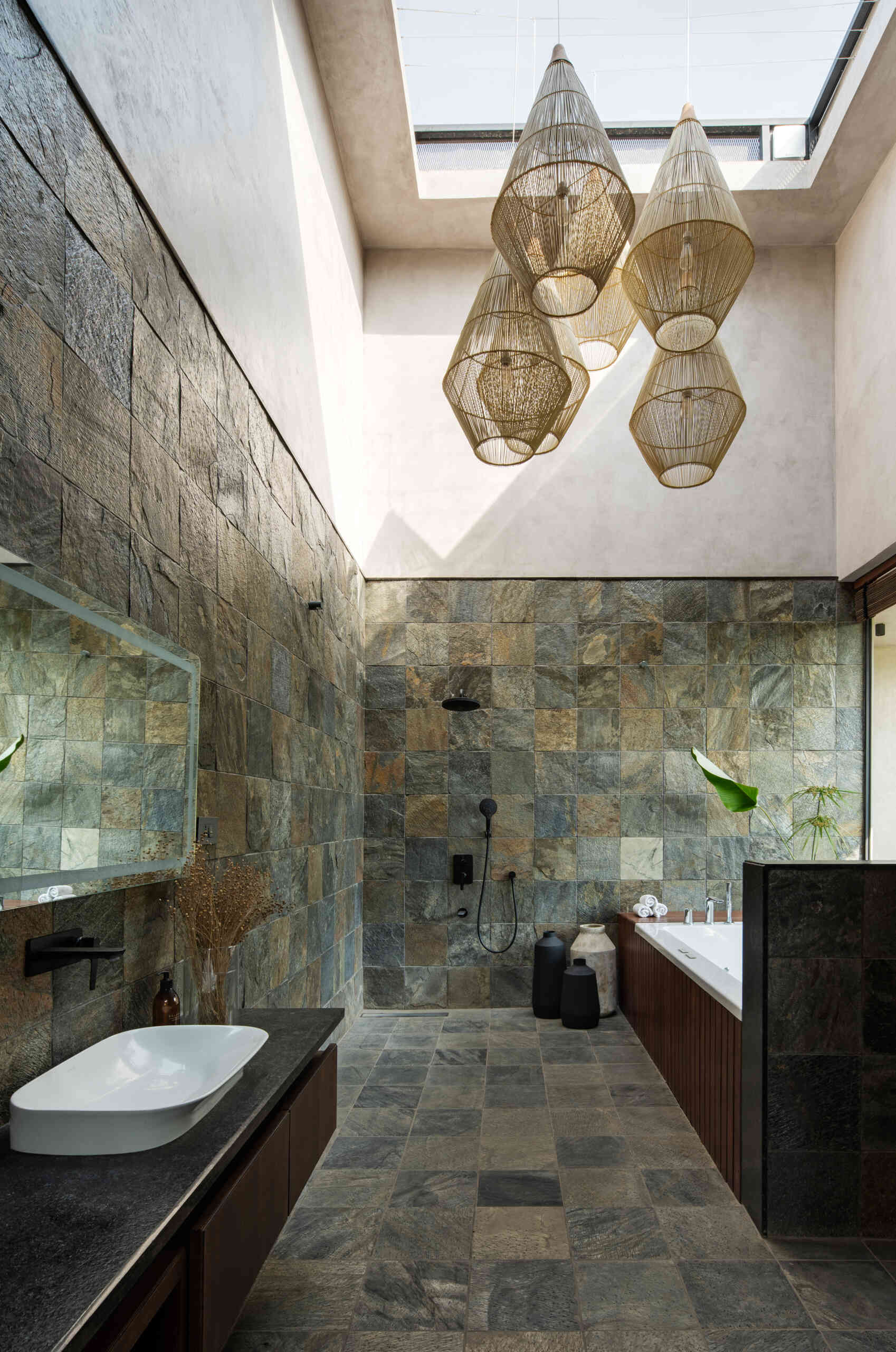 Stone tiled bathrooms that keep the palette natural and calm, echoing the home’s outdoor textures.