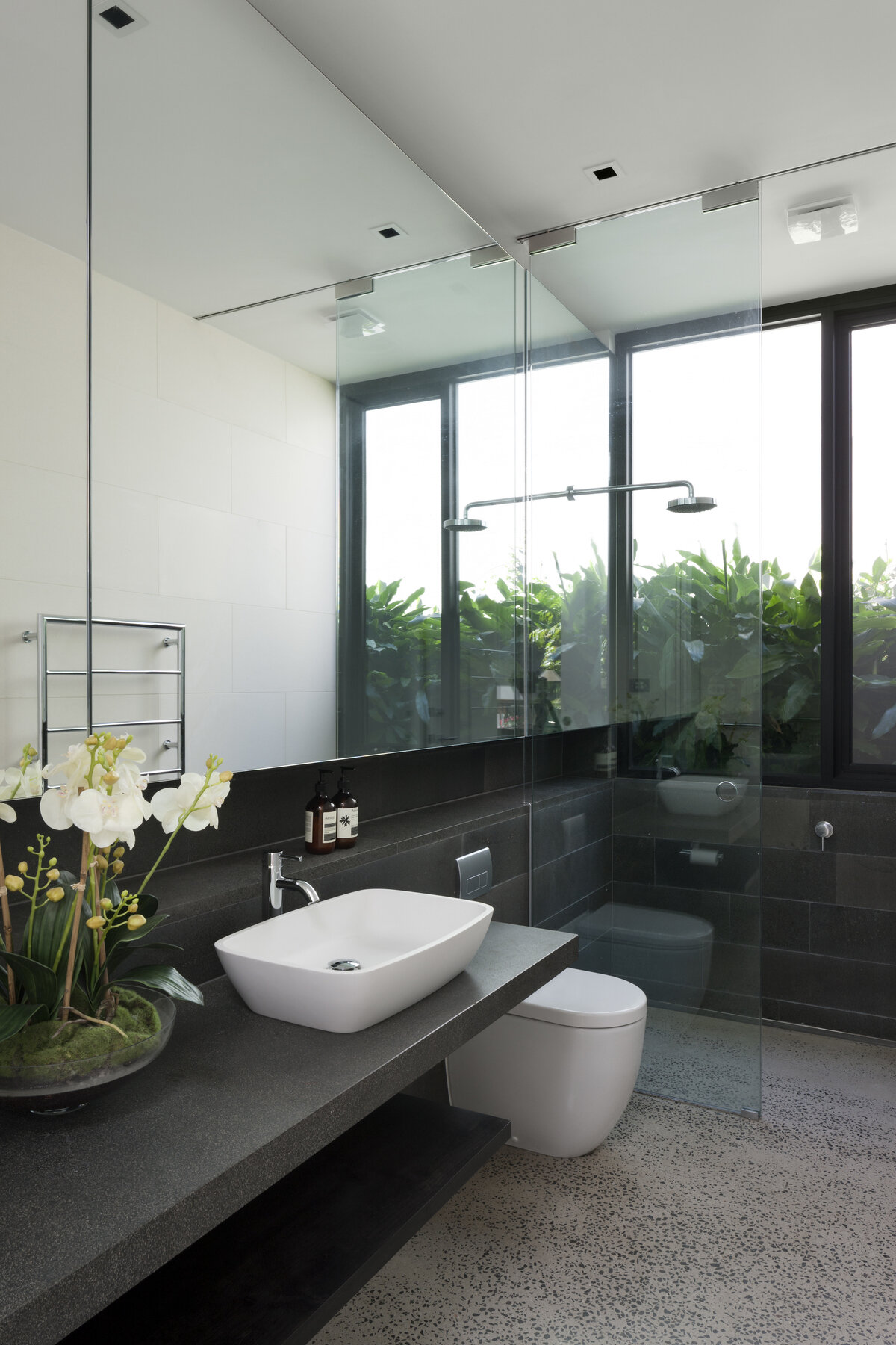 A bathroom with a large window runs from the vanity through to the shower, helping to reflect light throughout the room and keeping the space calm and bright.