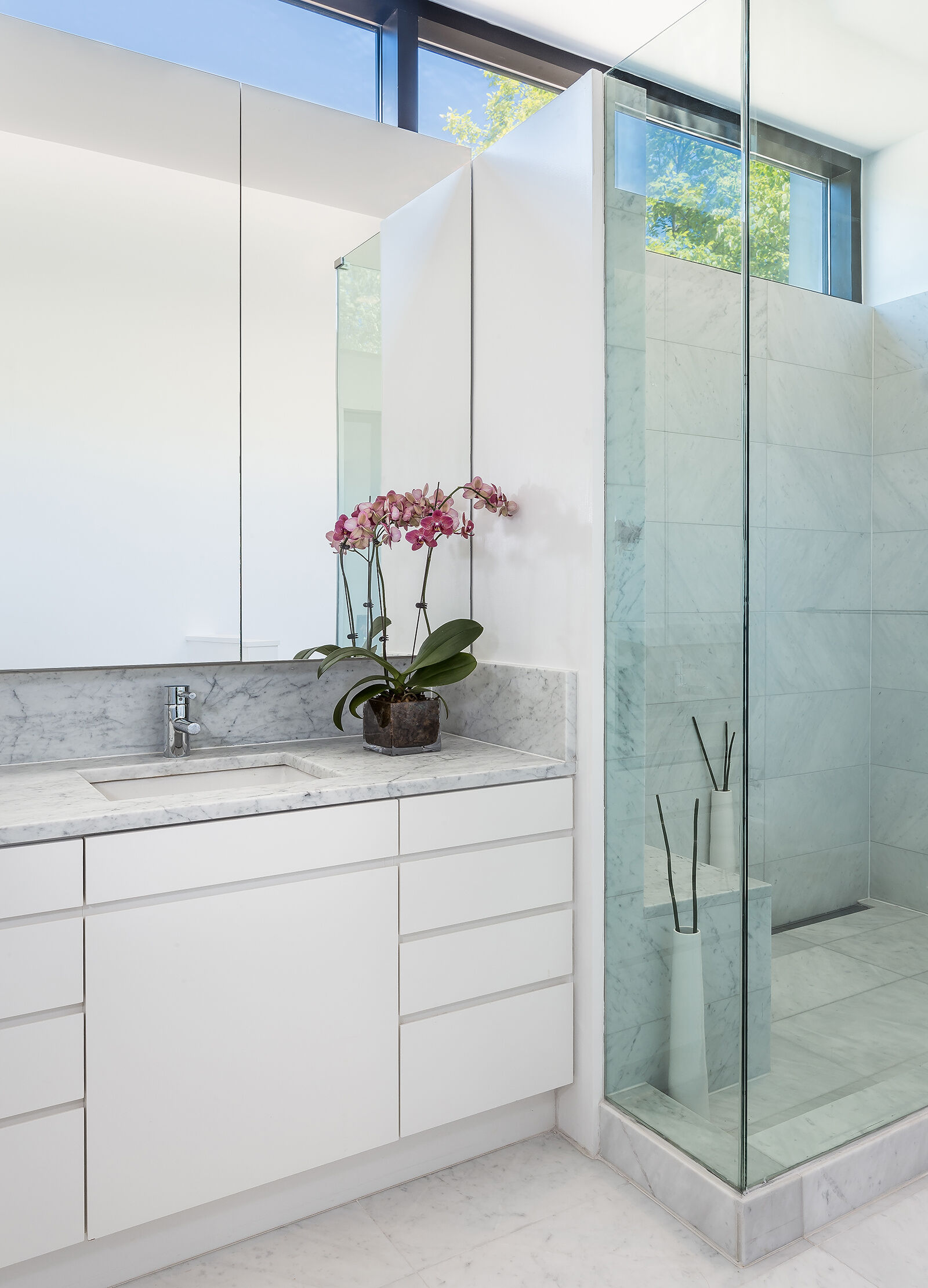A bright, minimalist bathroom that reflects the light and serenity of its forest surroundings.