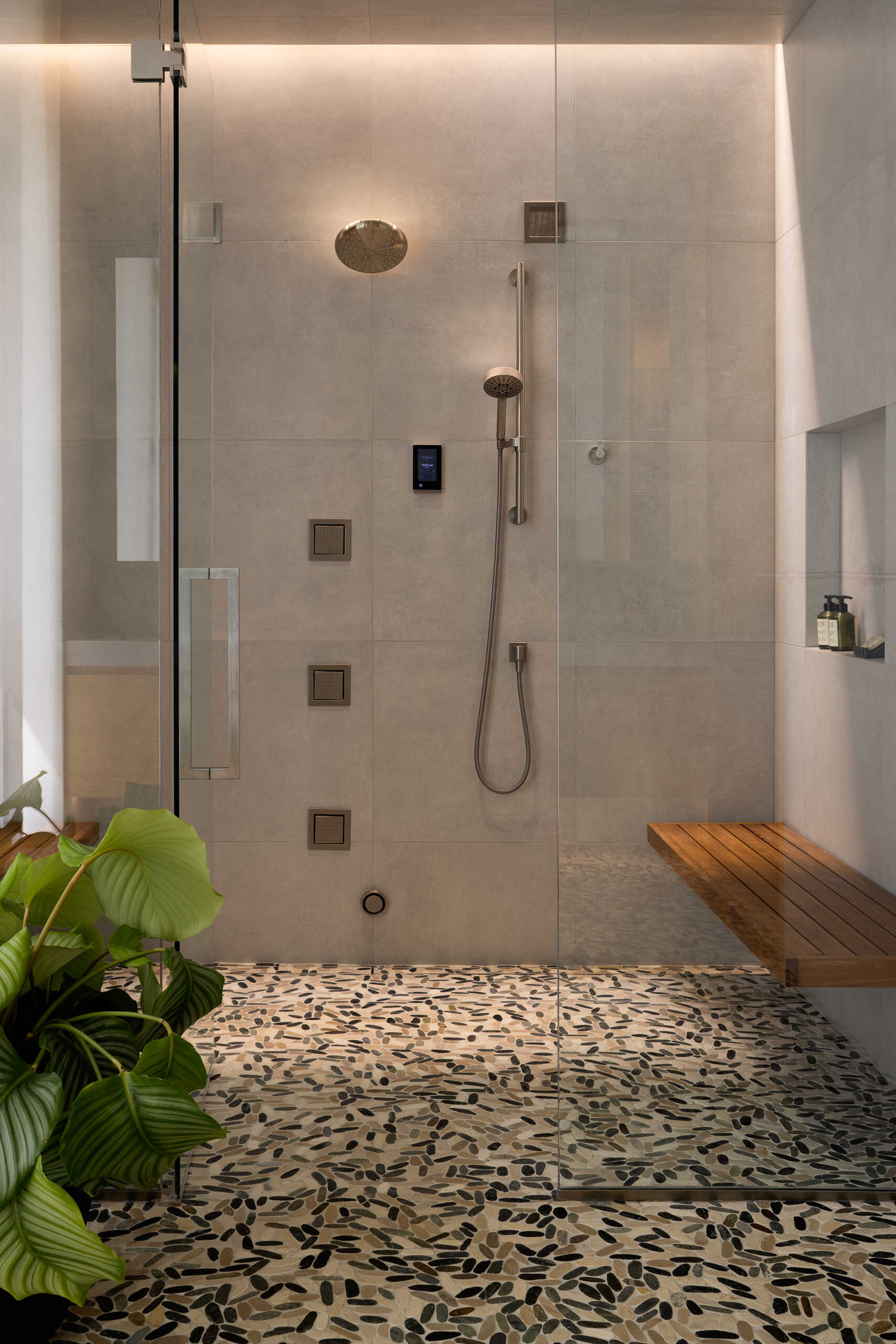A spa inspired bathroom with pebble flooring, seamless sinks, and soft lighting brings quiet luxury to the home.