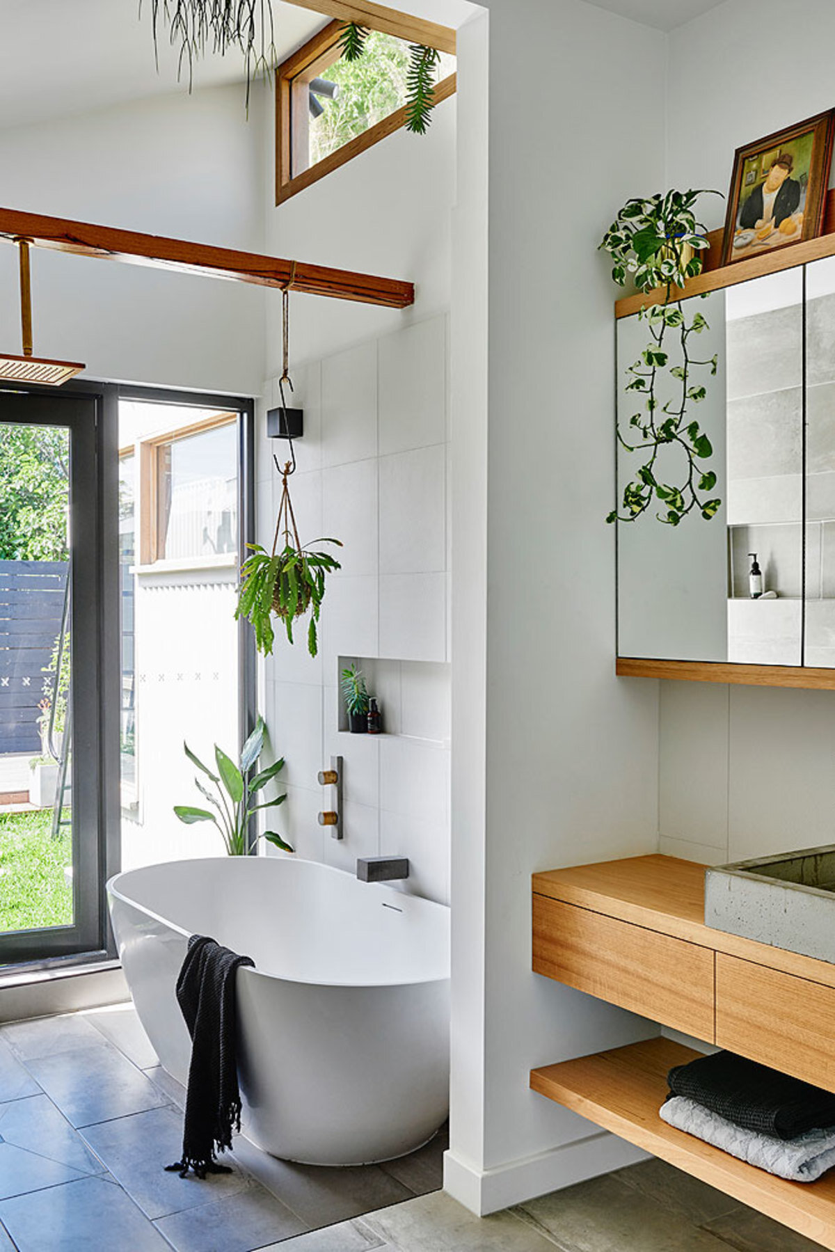 A refreshed bathroom with a freestanding bathtub, timber accents and plants for a natural and soothing look.