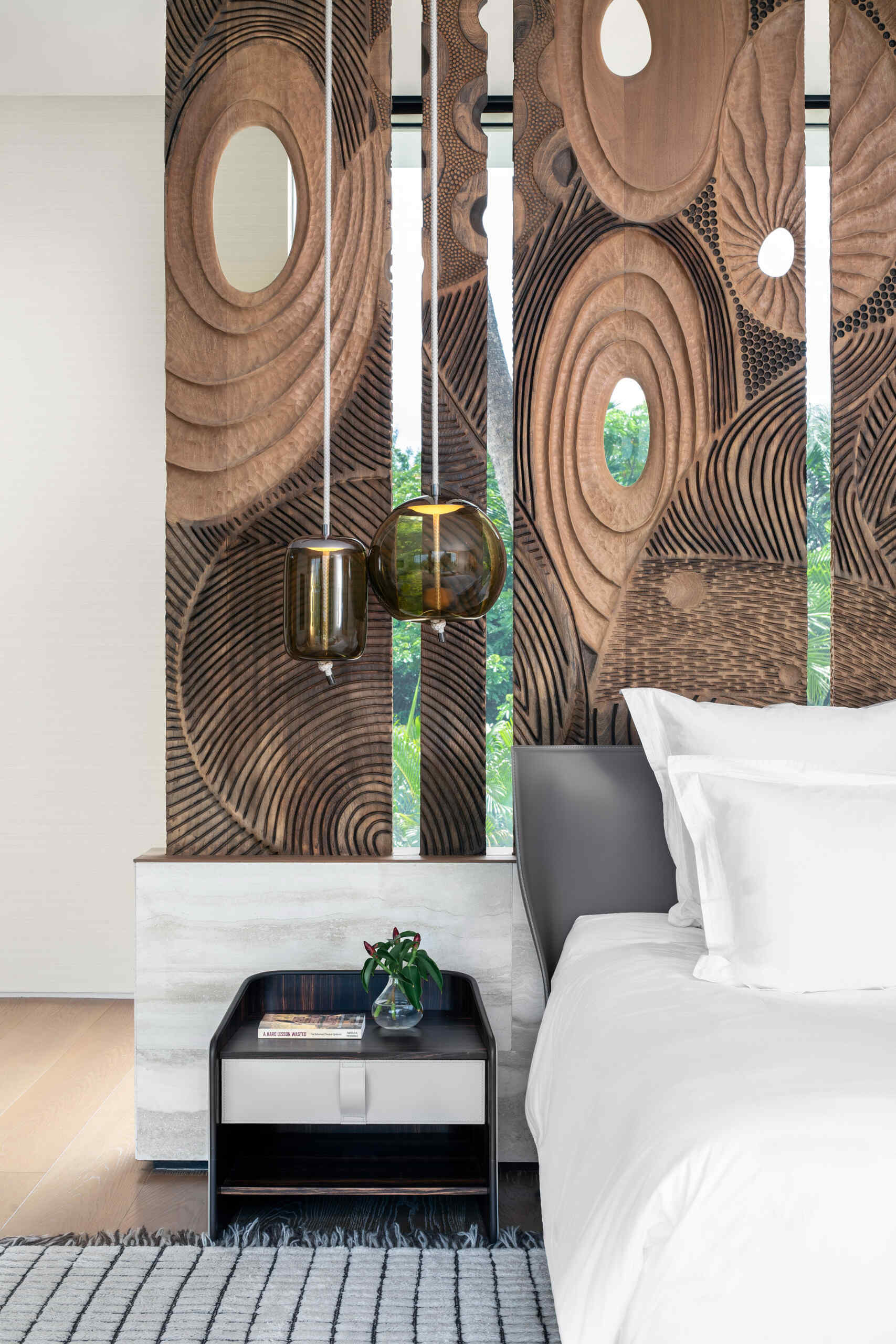 Interiors, like this bedroom, are filled with timber, stone, and local artwork create a warm contrast to the clean architecture.