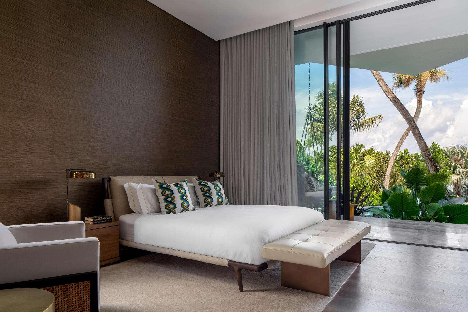 Interiors, like this bedroom, are filled with timber, stone, and local artwork create a warm contrast to the clean architecture.