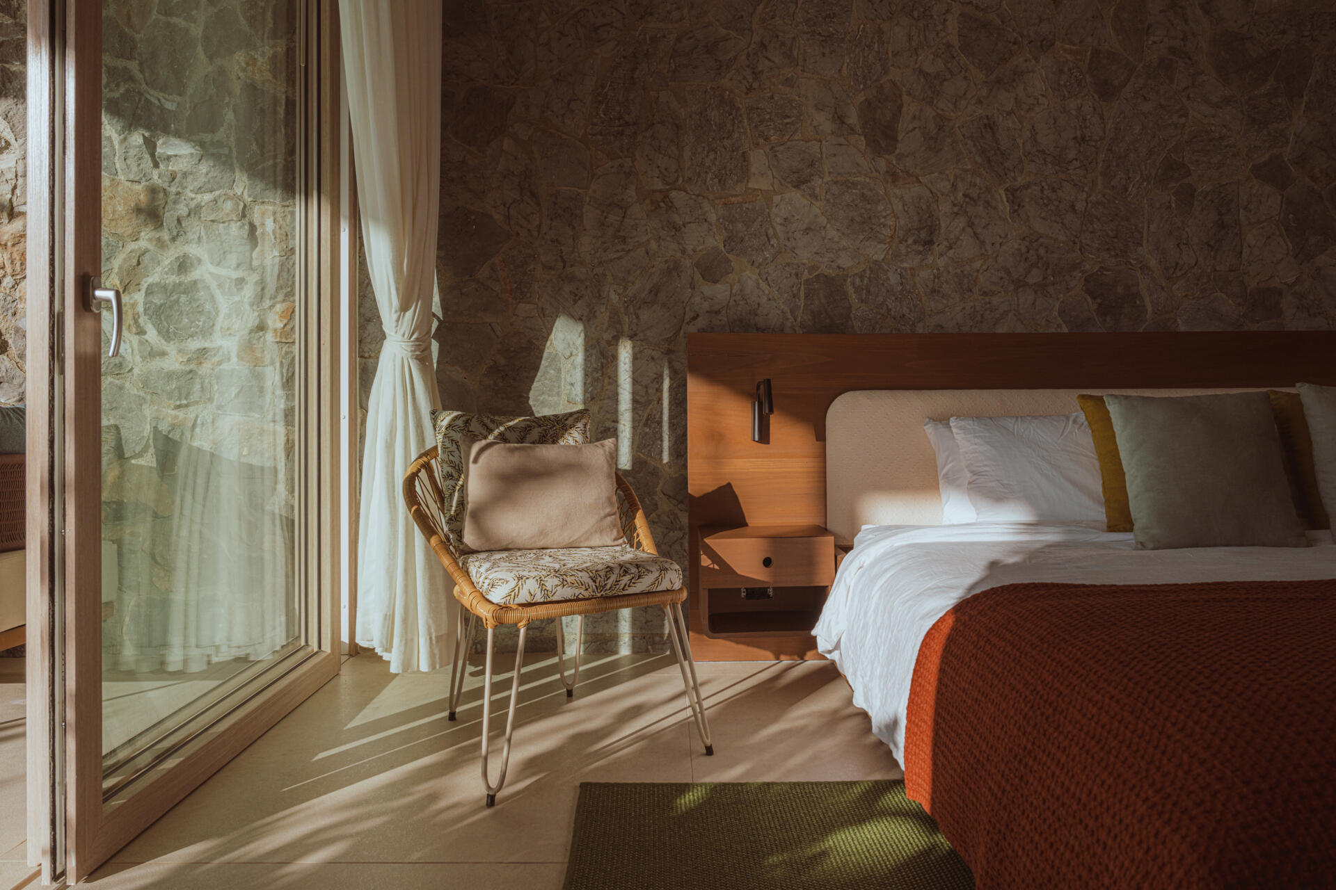 This bedroom with a stone wall opens to a private patio.