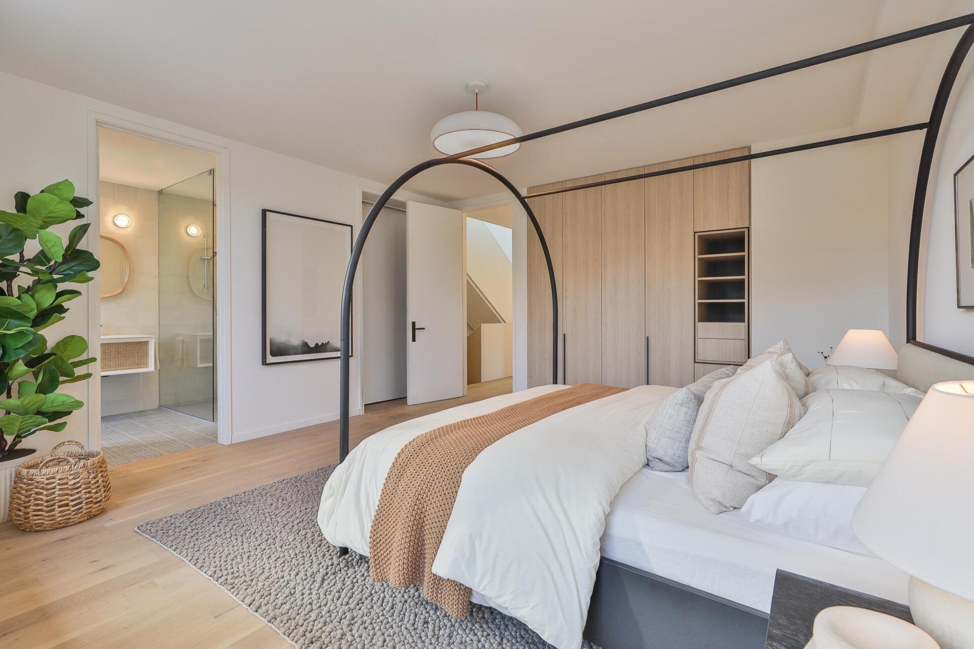 Matte white and quarter cut oak built ins keep the palette calm. The bathroom unfolds in blue tones and subtle patterns that echo the home’s quiet material rigor.