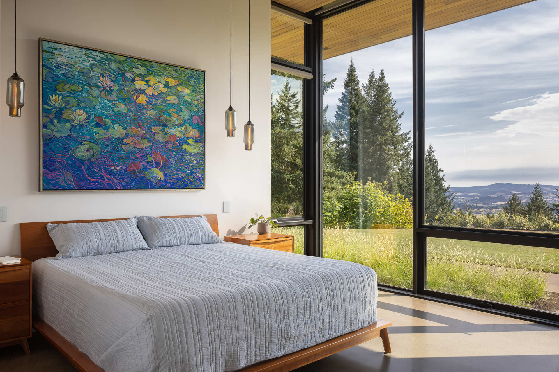 A serene bedroom with floor to ceiling windows captures endless valley views and gentle morning light.