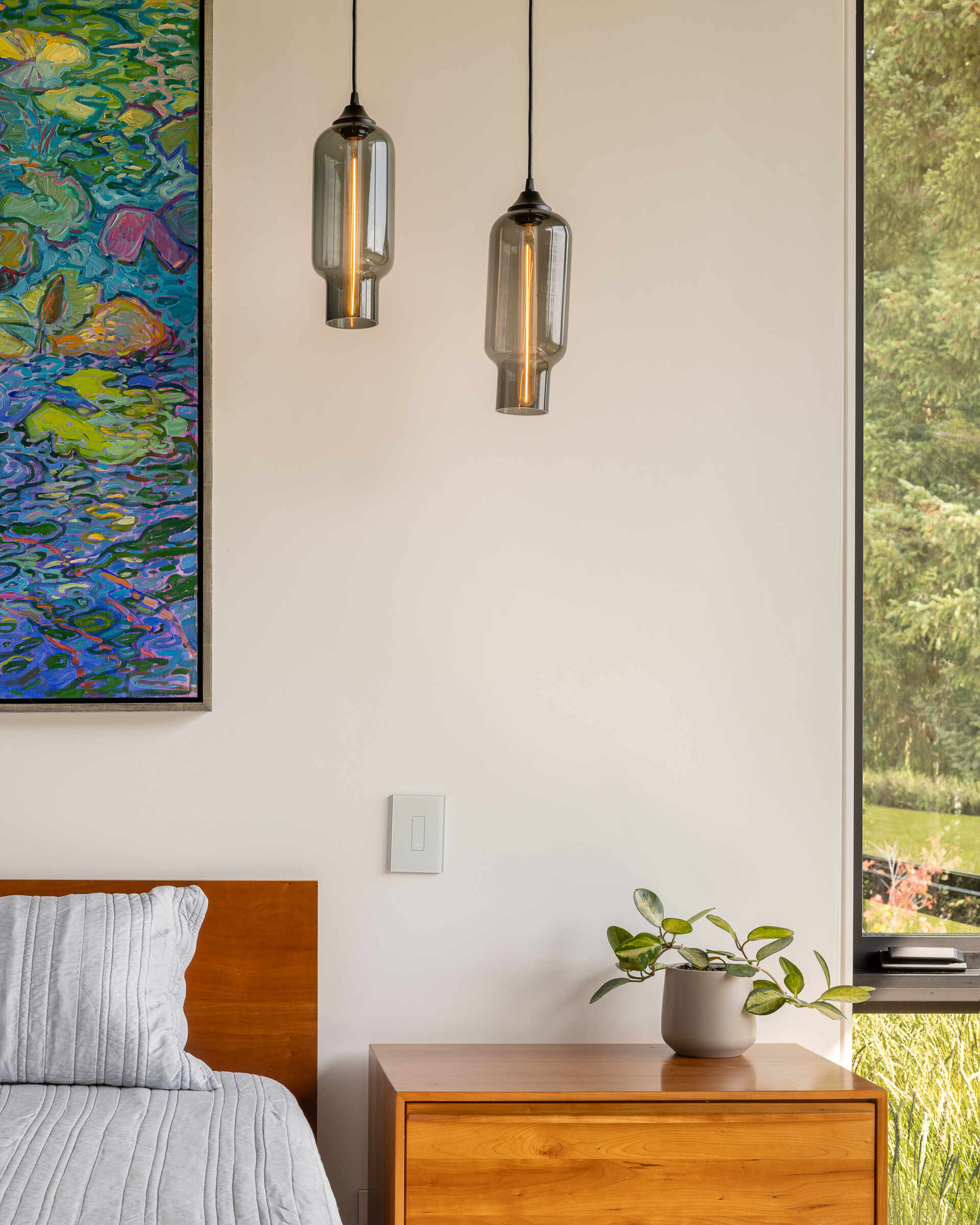 A serene bedroom with floor to ceiling windows captures endless valley views and gentle morning light.