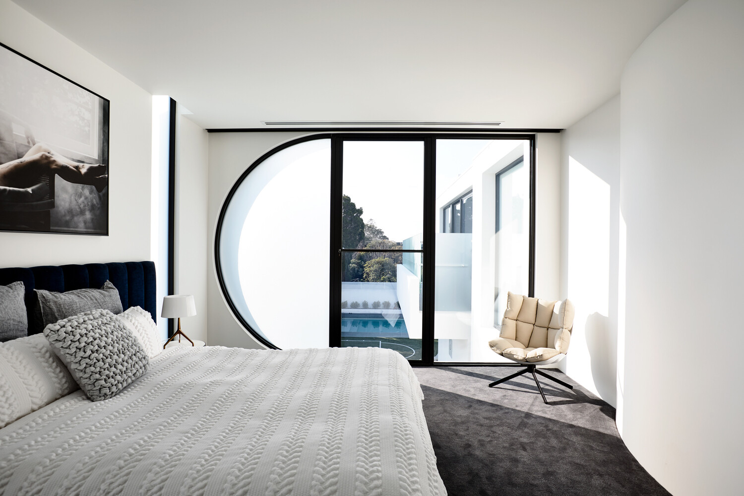 A serene bedroom with backyard views and a frosted half circle window that keeps the space bright and private.