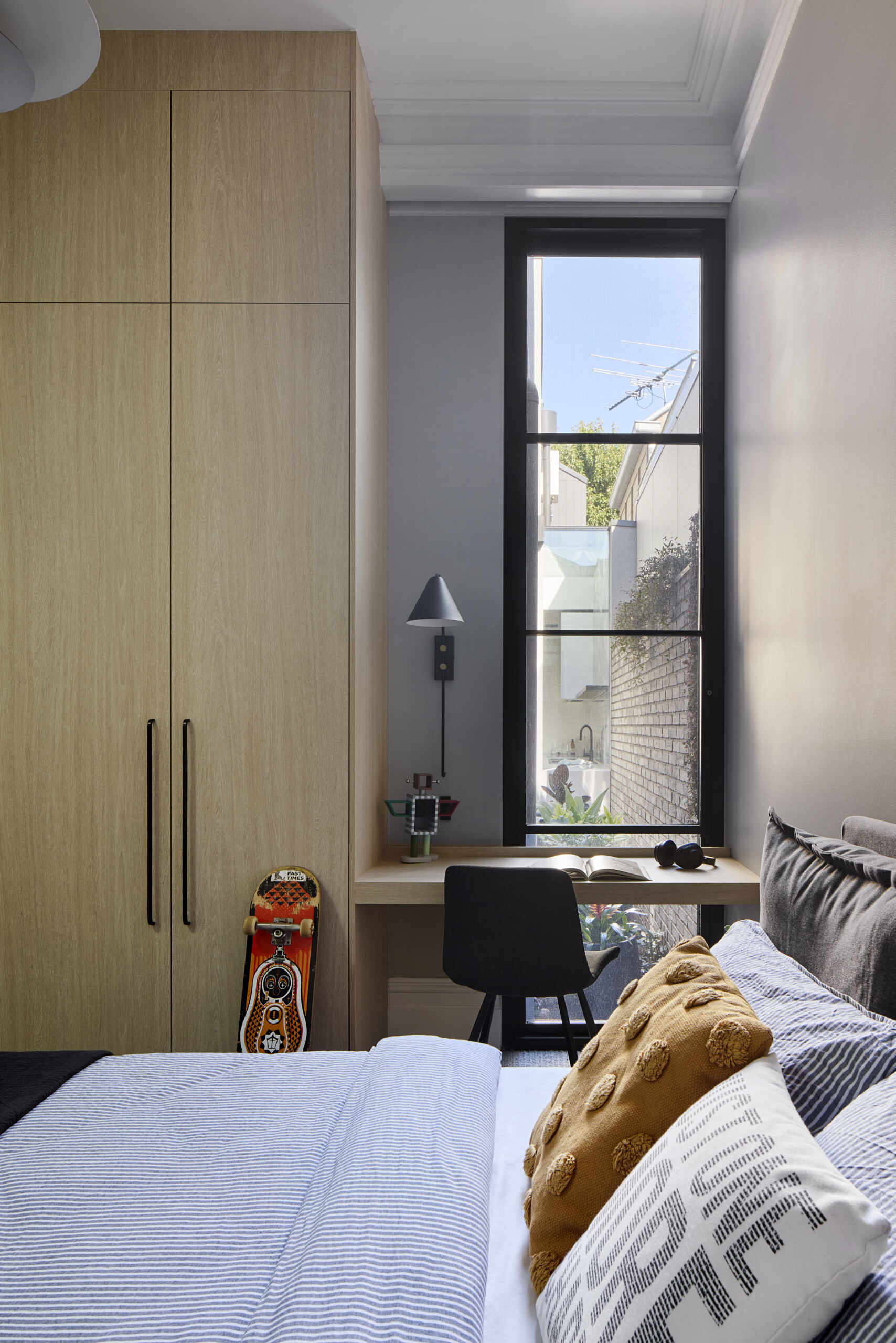 A modern bedroom with built-in wood closets and desk.