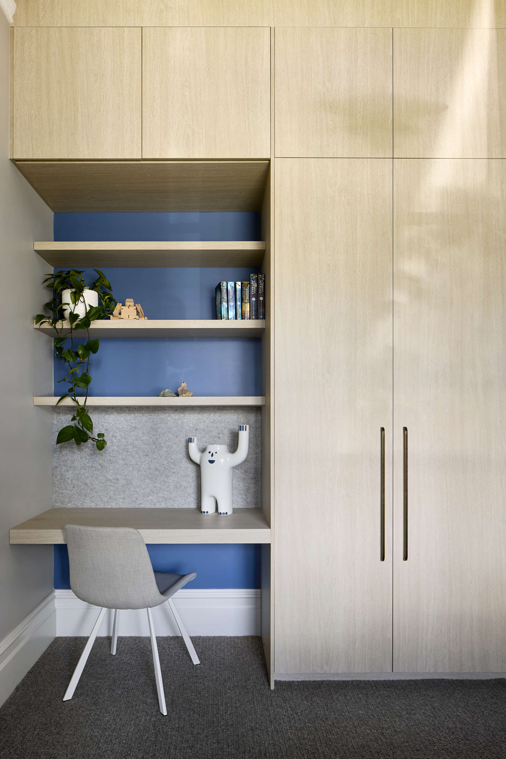 A modern bedroom with built-in wood closets and desk.