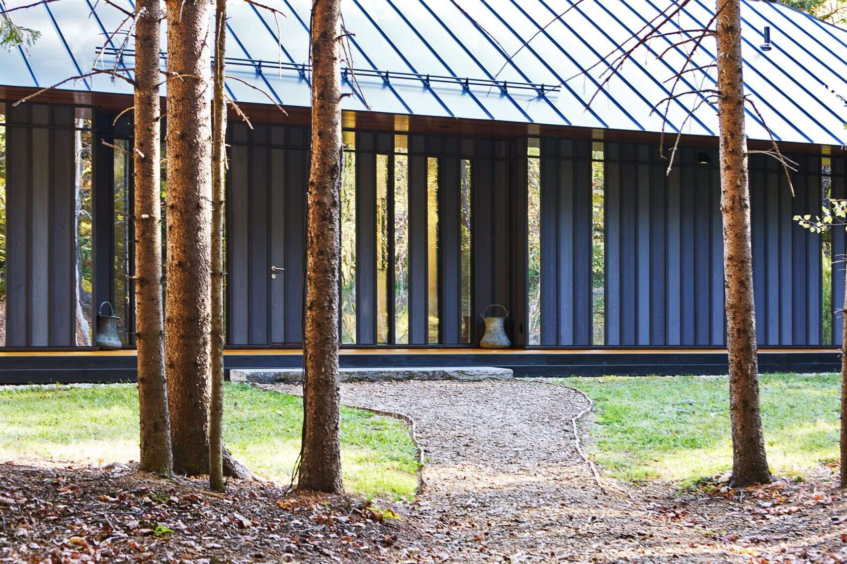 The Board + Batten guest house pairs painted boards with mirror-polished stainless steel panels to reflect the surrounding meadow and trees.