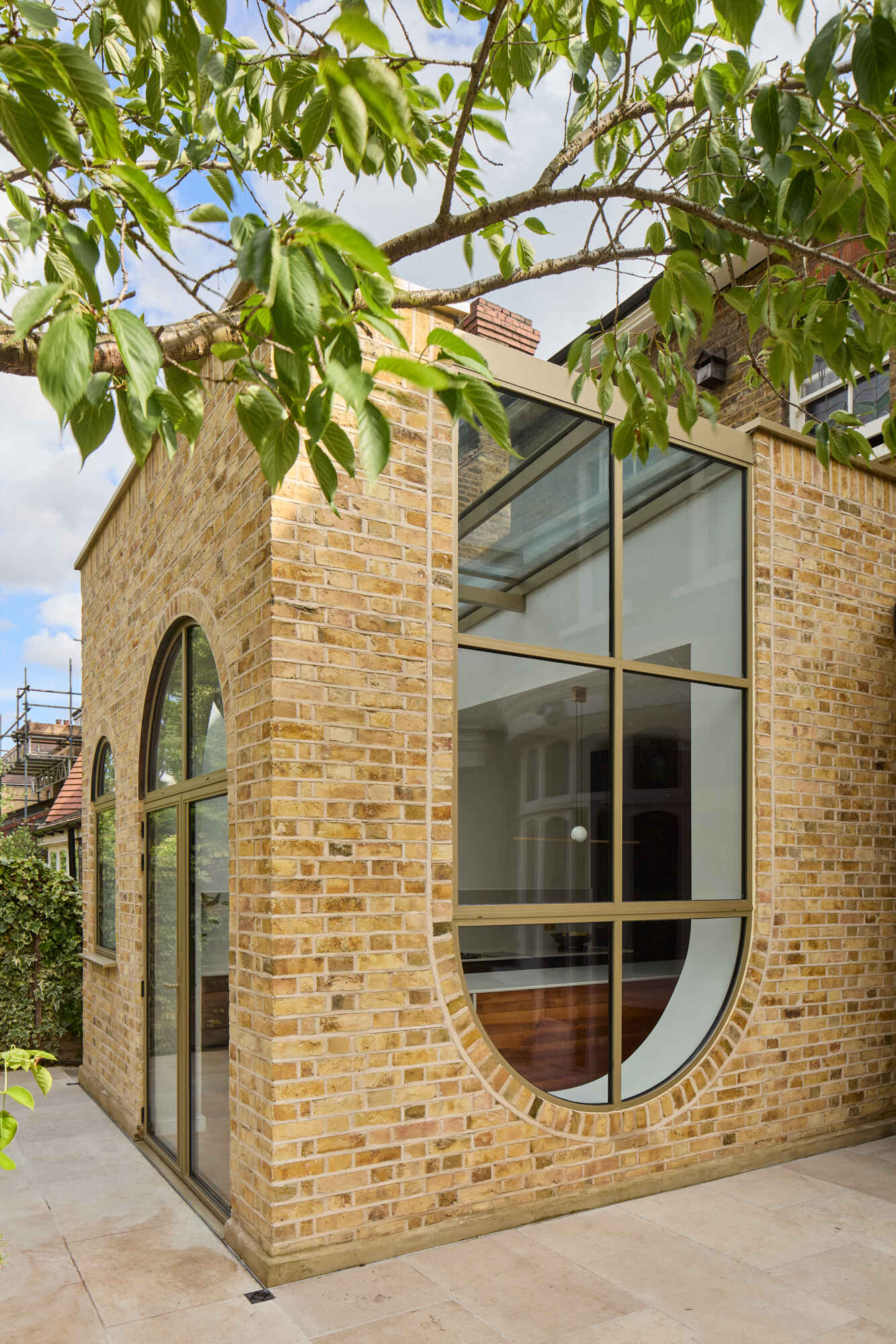 This rear extension of Perry Vale House reinterprets Edwardian craftsmanship with playful arches, reclaimed yellow London Stock Brick, and metallic bronze framing.