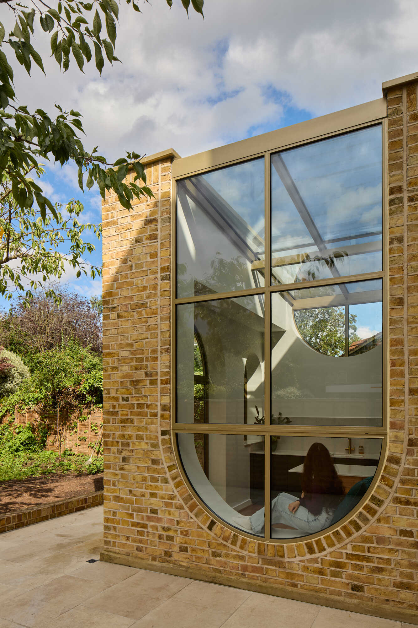 This rear extension of Perry Vale House reinterprets Edwardian craftsmanship with playful arches, reclaimed yellow London Stock Brick, and metallic bronze framing.