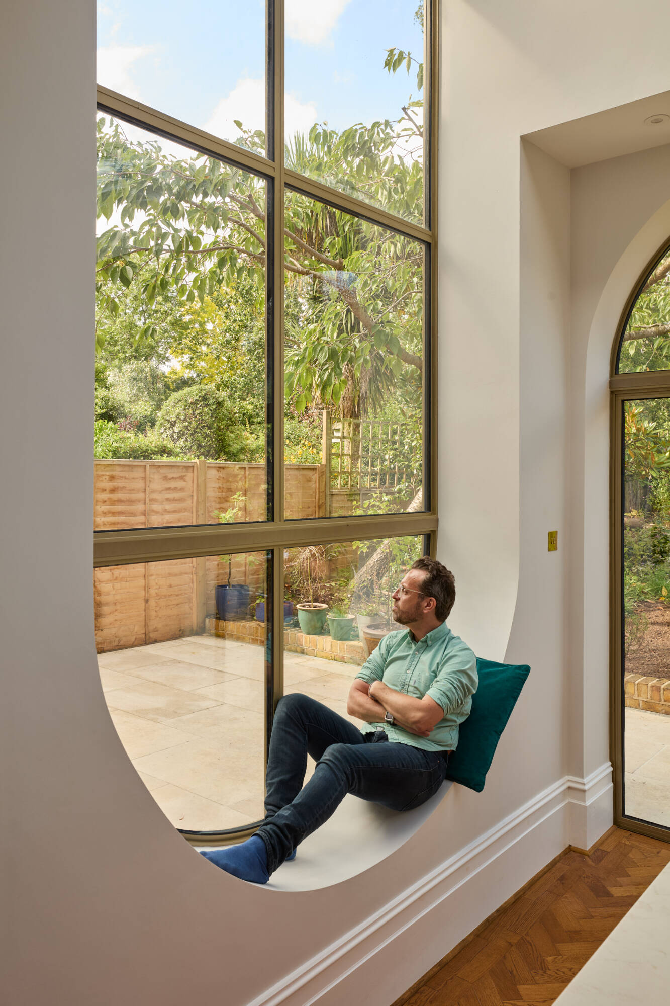In the kitchen of Perry Vale House, inverted arches and a wraparound glass roof fill the space with natural light. Soft grey cabinetry, marble worktops, and timber tones create a warm, modern feel that stays true to the home’s character.