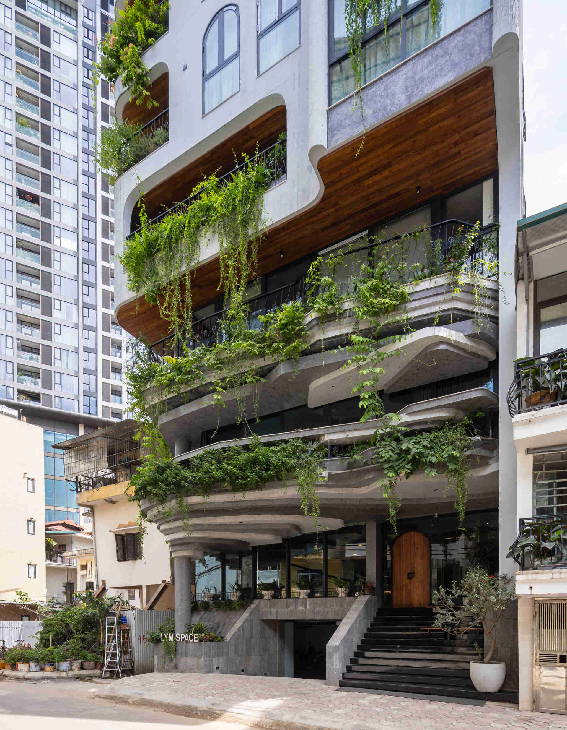 A serene, story-driven building in Hanoi that blends a bold vertical core with soft greenery, natural light, and gentle architectural rhythms to express resilience and quiet elegance in the city.