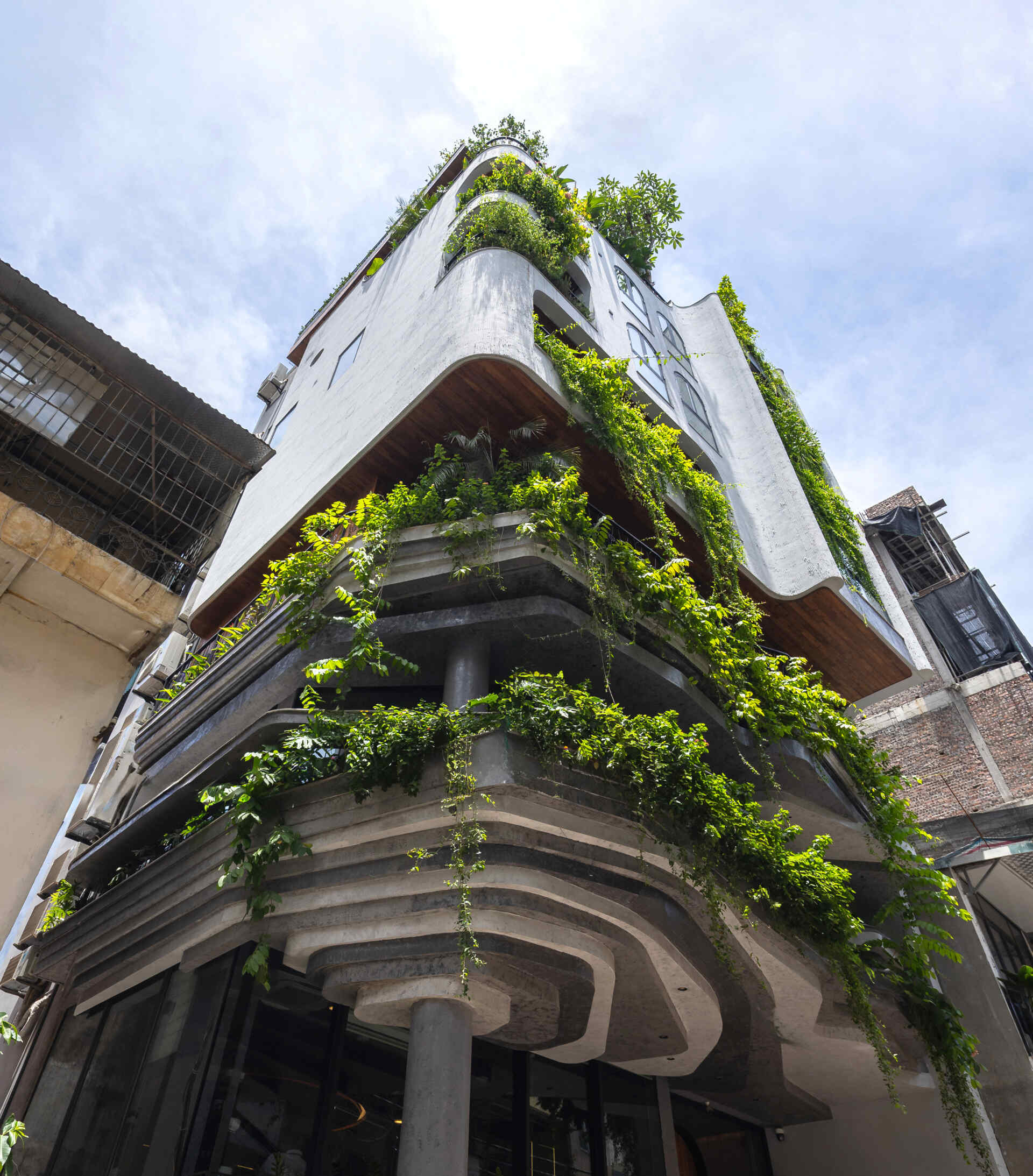 A serene, story-driven building in Hanoi that blends a bold vertical core with soft greenery, natural light, and gentle architectural rhythms to express resilience and quiet elegance in the city.