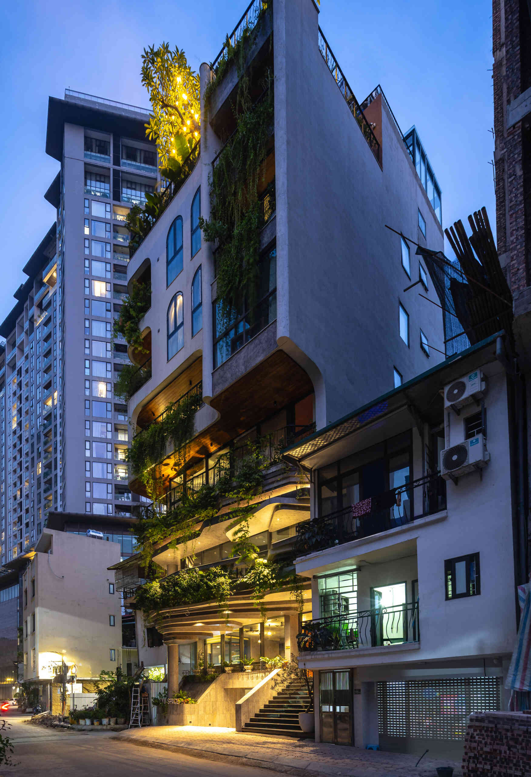 A serene, story-driven building in Hanoi that blends a bold vertical core with soft greenery, natural light, and gentle architectural rhythms to express resilience and quiet elegance in the city.