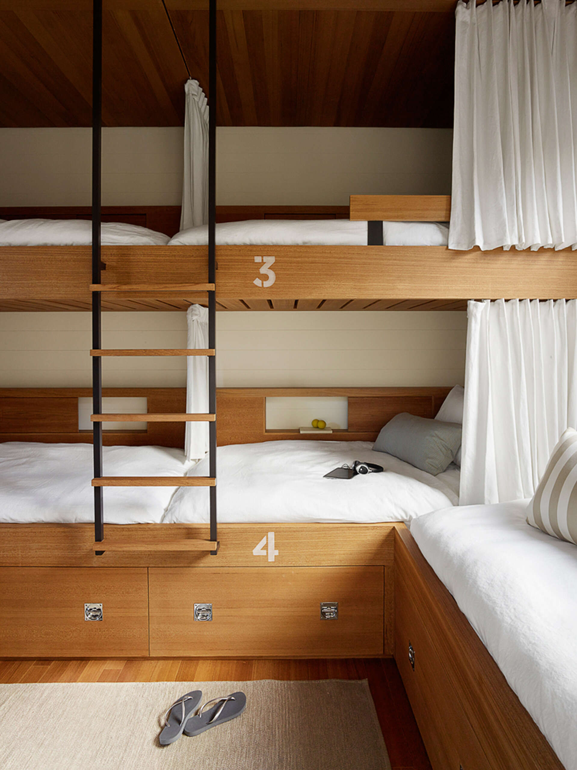 A bunk room brings a playful twist, with built-in beds that feel straight out of a ship’s cabin, each one cleverly numbered, perfect for visiting friends and family.