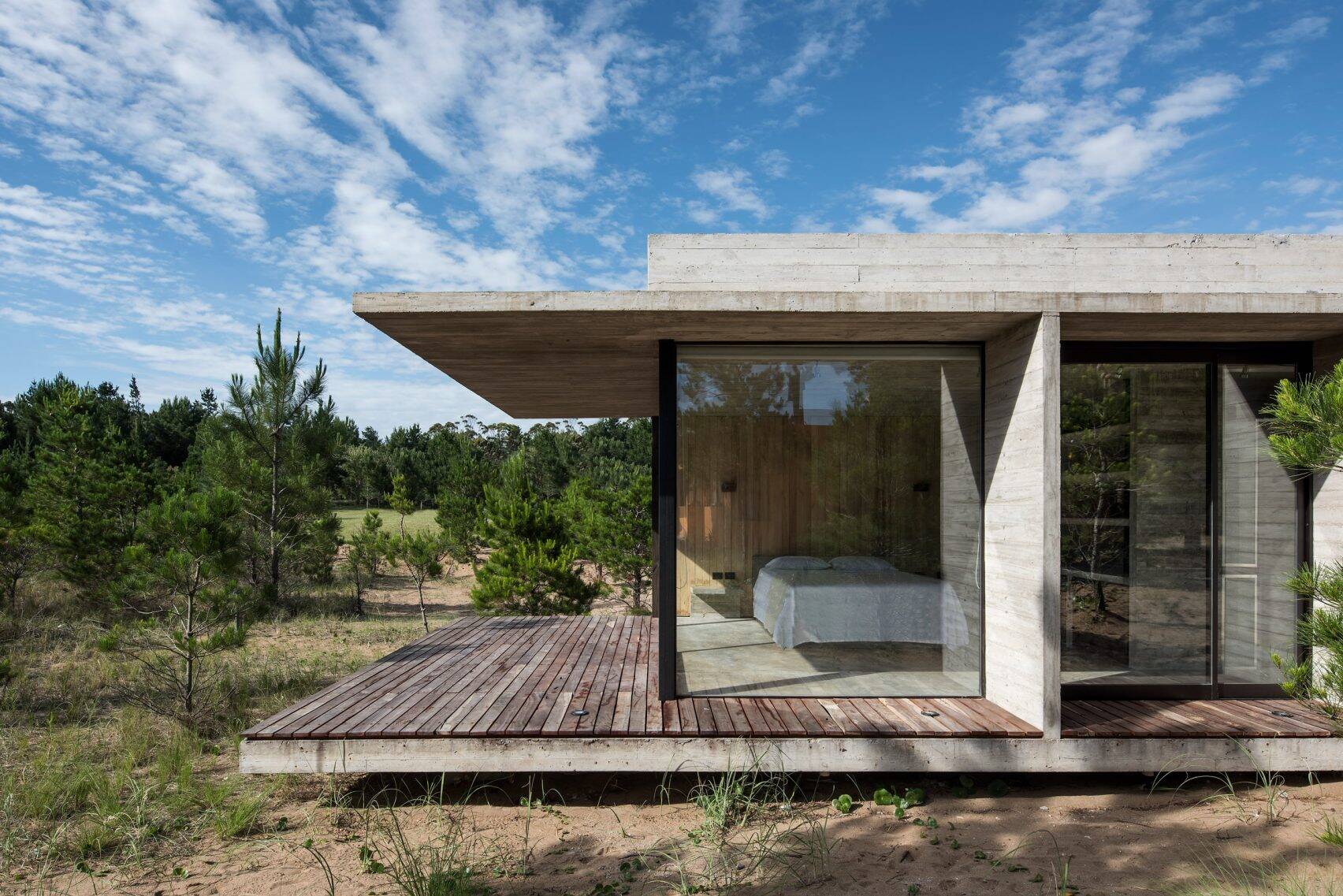 A weathered wood deck blends into the forest and contrasts with the concrete structure for a natural finish.