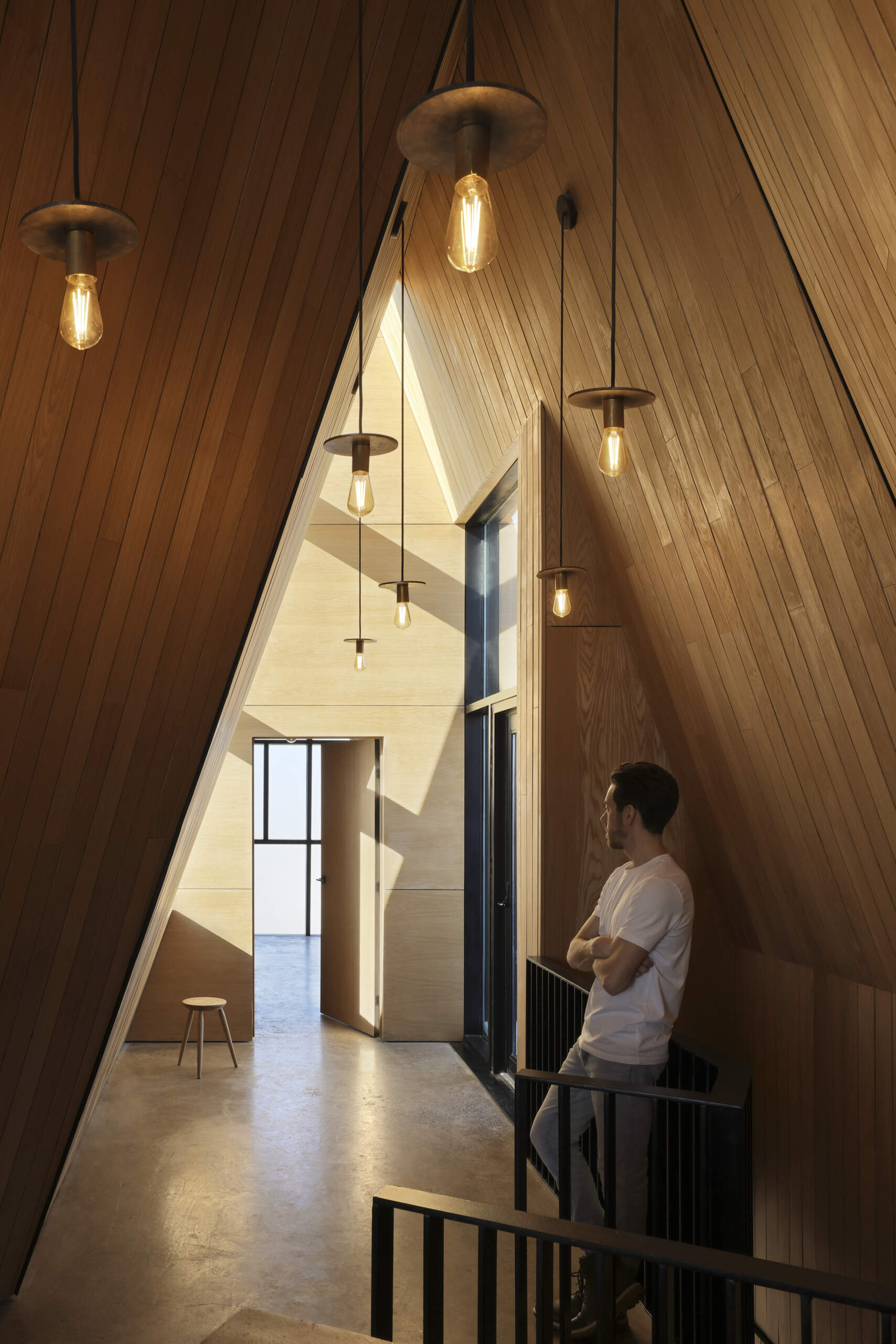 Inside this modern cottage, the atmosphere is warm and simple with white oak clad walls and polished concrete floors. The great room is organized into three zones for gathering, eating, and cooking, each set at its own elevation.