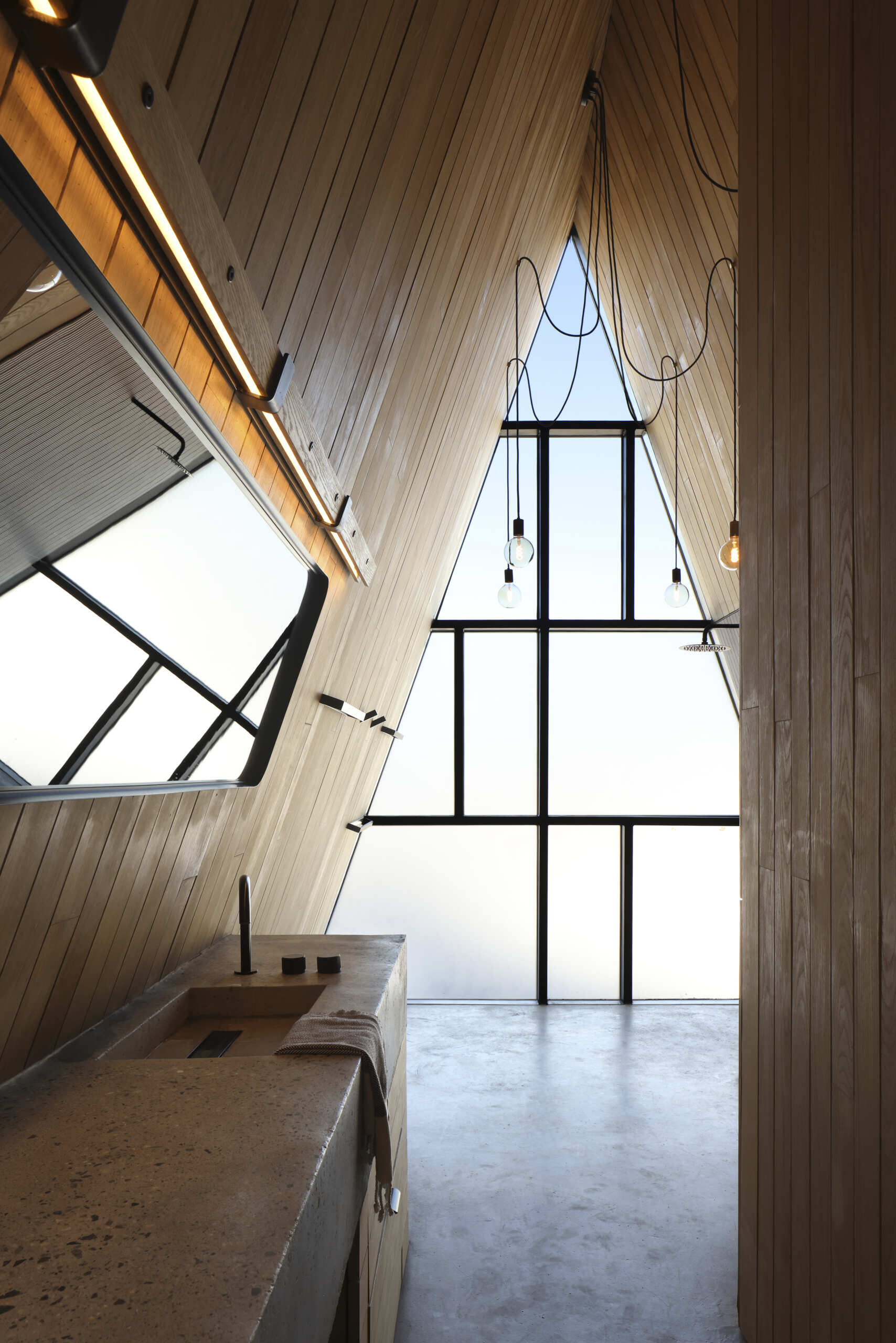 A modern bathroom inside a cottage with a wall of frosted windows.