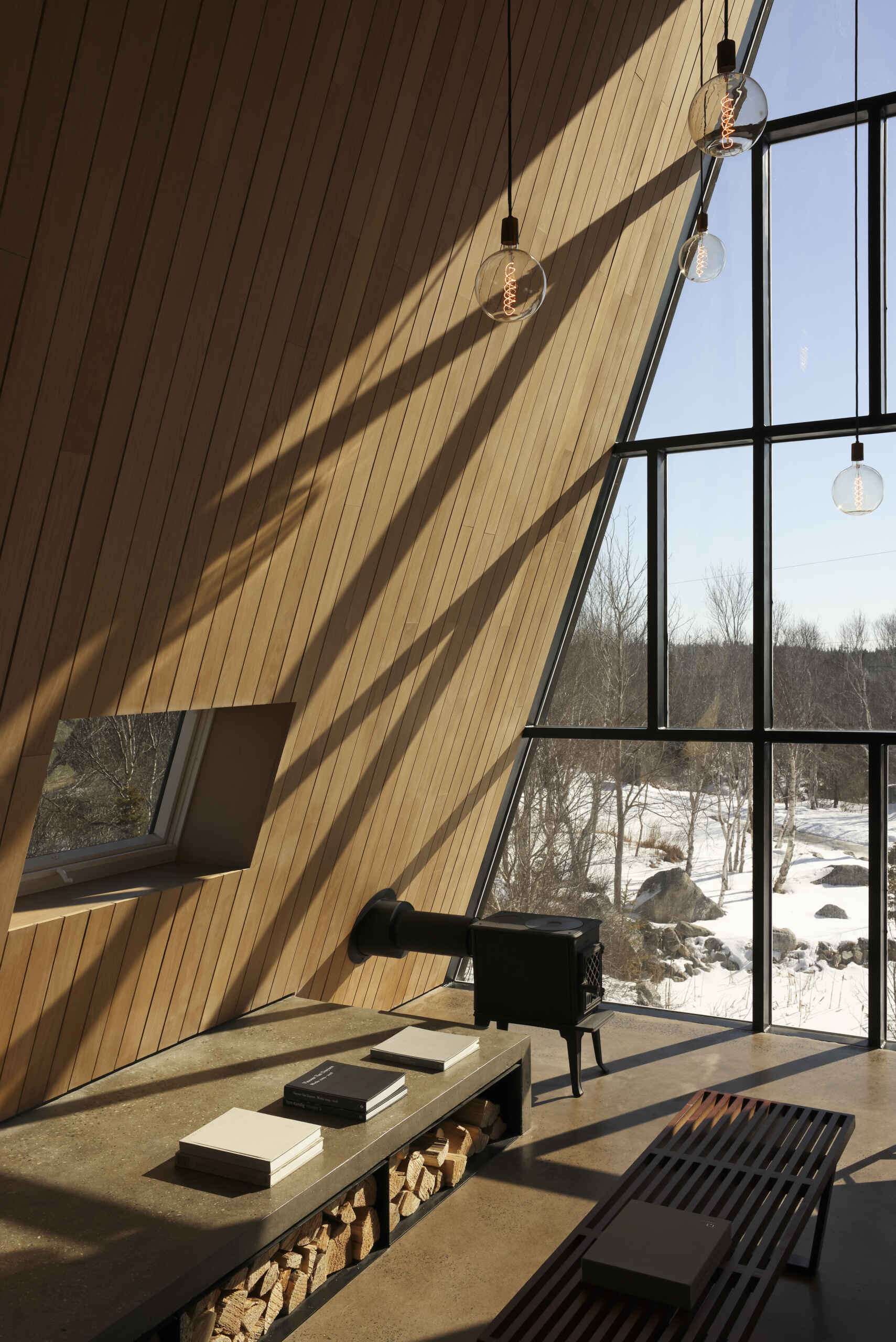 Inside this modern cottage, the atmosphere is warm and simple with white oak clad walls and polished concrete floors. The great room is organized into three zones for gathering, eating, and cooking, each set at its own elevation.